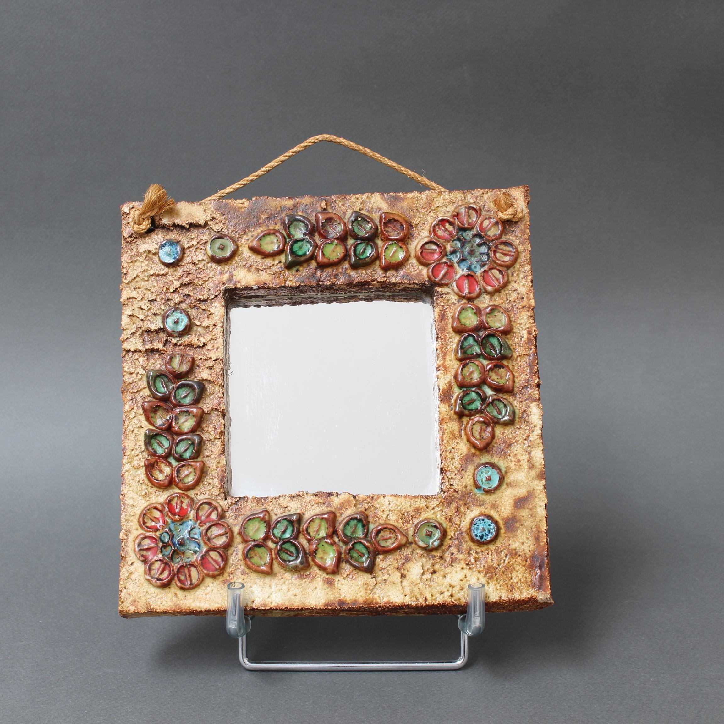 Vintage-Wandspiegel aus Keramik mit Blumenmotiv, zugeschrieben La Roue, Vallauris, Frankreich (ca. 1960er Jahre). Ein charmanter, dekorativer Spiegel mit rustikalen, aber farbenfrohen Details, die das quadratische Spiegelglas umgeben. In sehr gutem