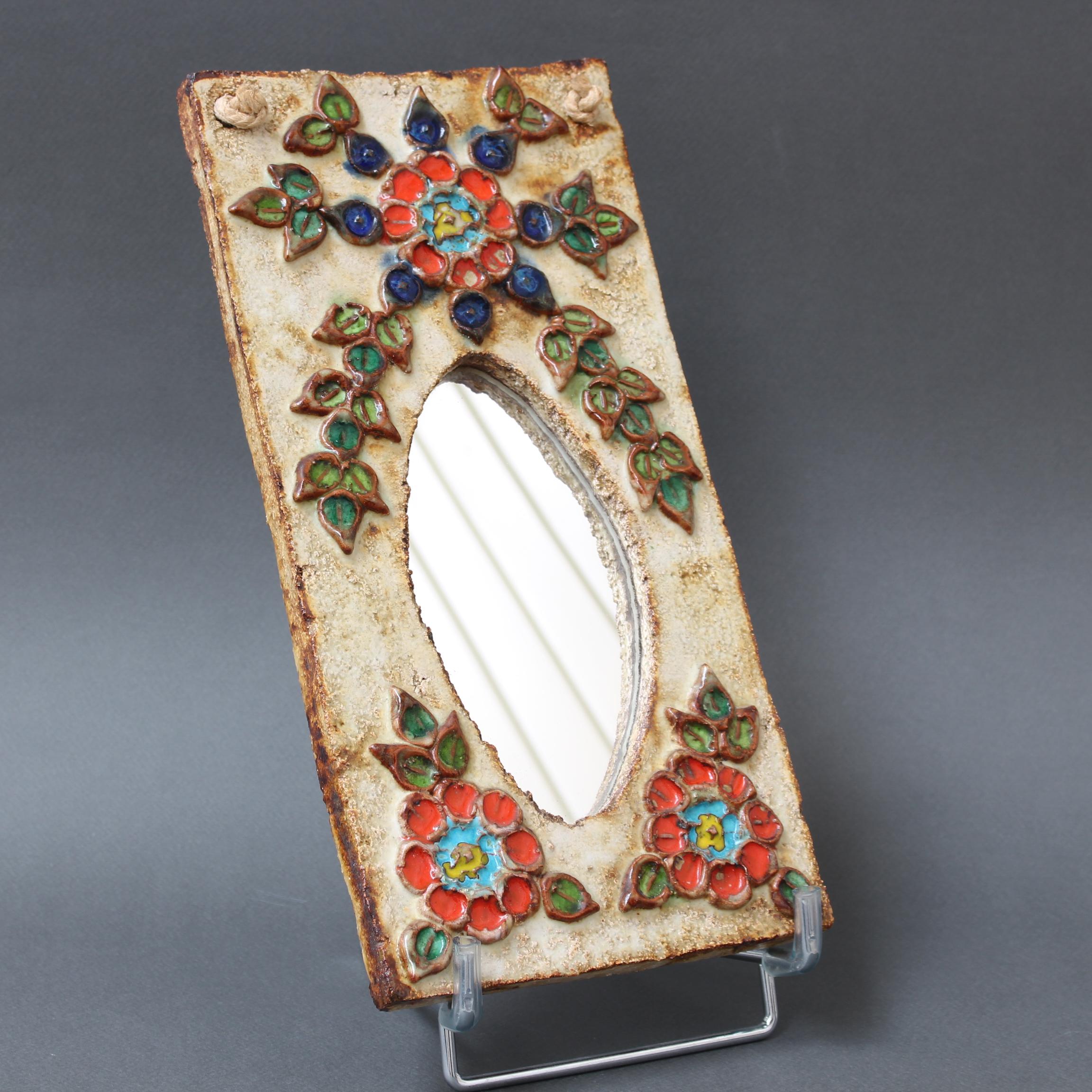 Ceramic flower-motif wall mirror with glazed leaves attributed to La Roue, Vallauris, France (circa 1960s). A charming, decorative small mirror with rustic but colourful details surrounding the elongated, rectangular mirror. A hanging cord runs