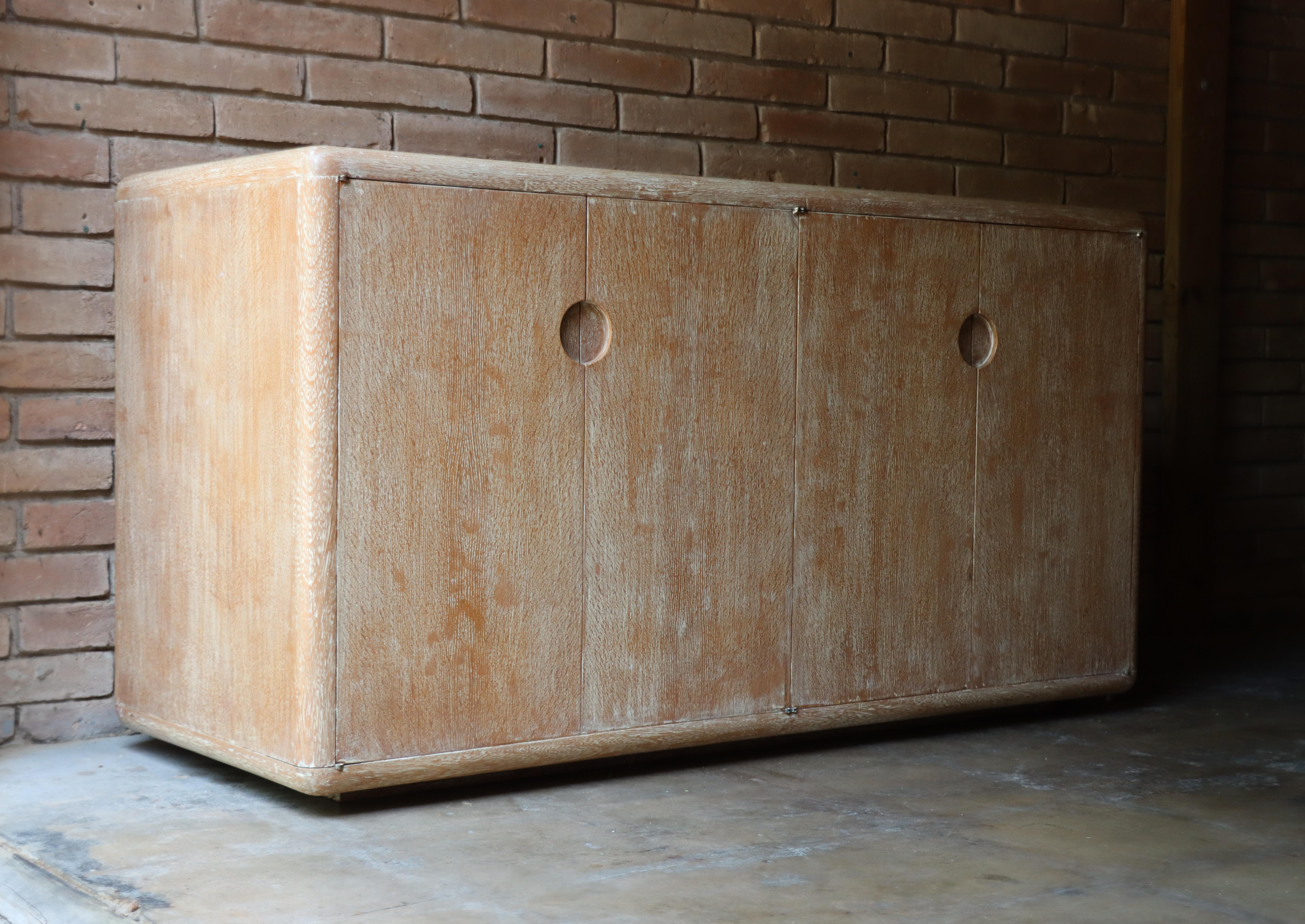 Stunning four door cabinet circle of Jean-Michel Frank, France, c. 1950s. Executed in cerused white oak, this subtle detailed design eliminates all the unnecessary fuss. Its recessed circular door pulls and rounded edges don’t draw attention away