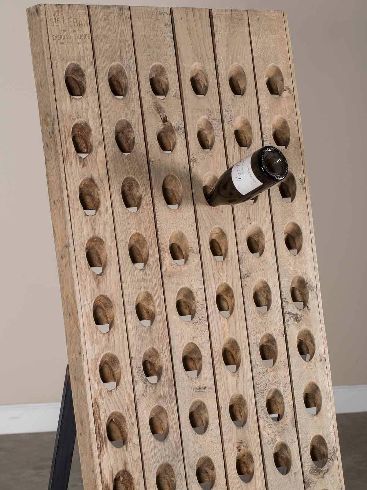 A terrific reuse of a traditional vintage champagne riddling rack mounted on a custom-made Industrial iron stand to create a custom wine storage rack. When champagne is in the fermenting process the bottles need to be turned on a regular schedule