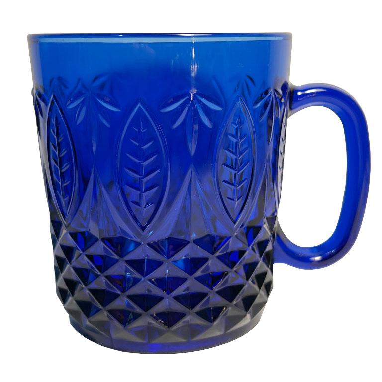A set of eight faceted cobalt blue royal sapphire tea or coffee mugs. This set is made in France, and created from a deep blue glass. Each mug has a handle in the same color on the side. The body of the cups have a faceted geometric lower half, and