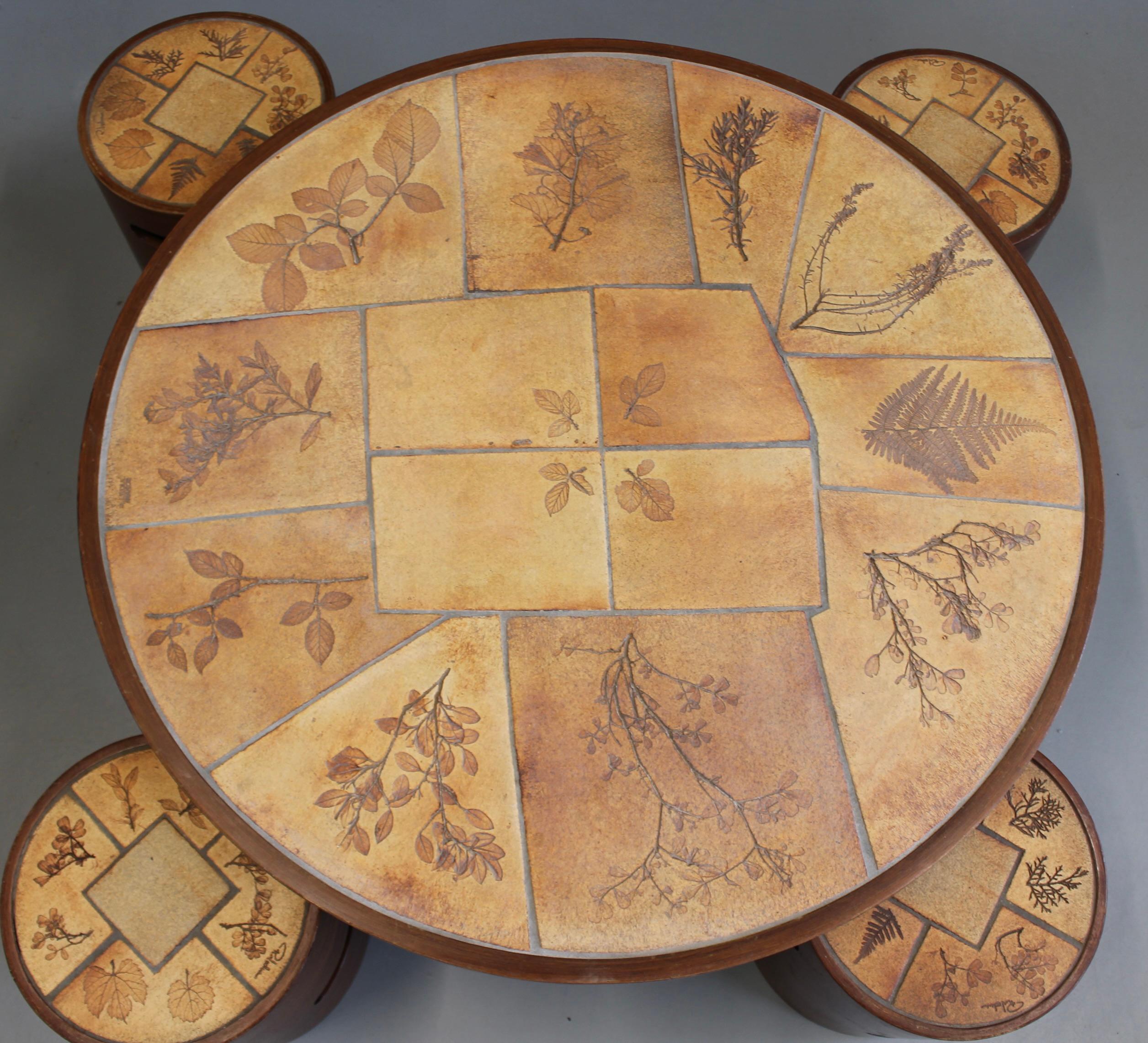 A rare and delightful ceramic coffee table set by French ceramicist Raymonde Leduc, dating to the 1970s. The round table top is inlaid with Leduc's iconic garrigue botanical tiles, each impressed with delicate foliage forms — leaves, branches, and