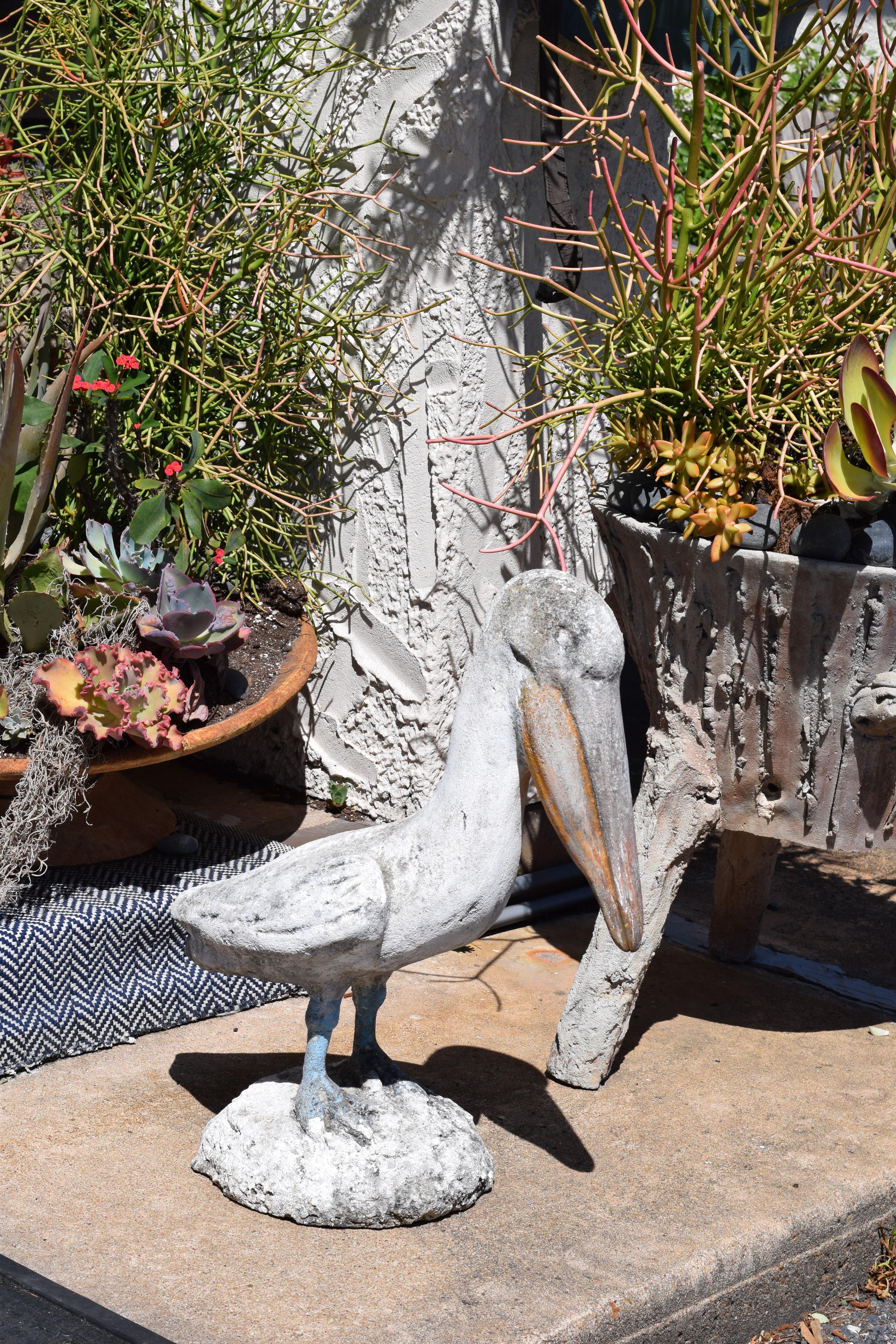 We found this colorful concrete pelican in France. Heavy and sturdy, the concrete bird stands solidly on a concrete base. The pelican and base retain traces of the original paint which has been worn and dulled by age into a soft patina. A perfect