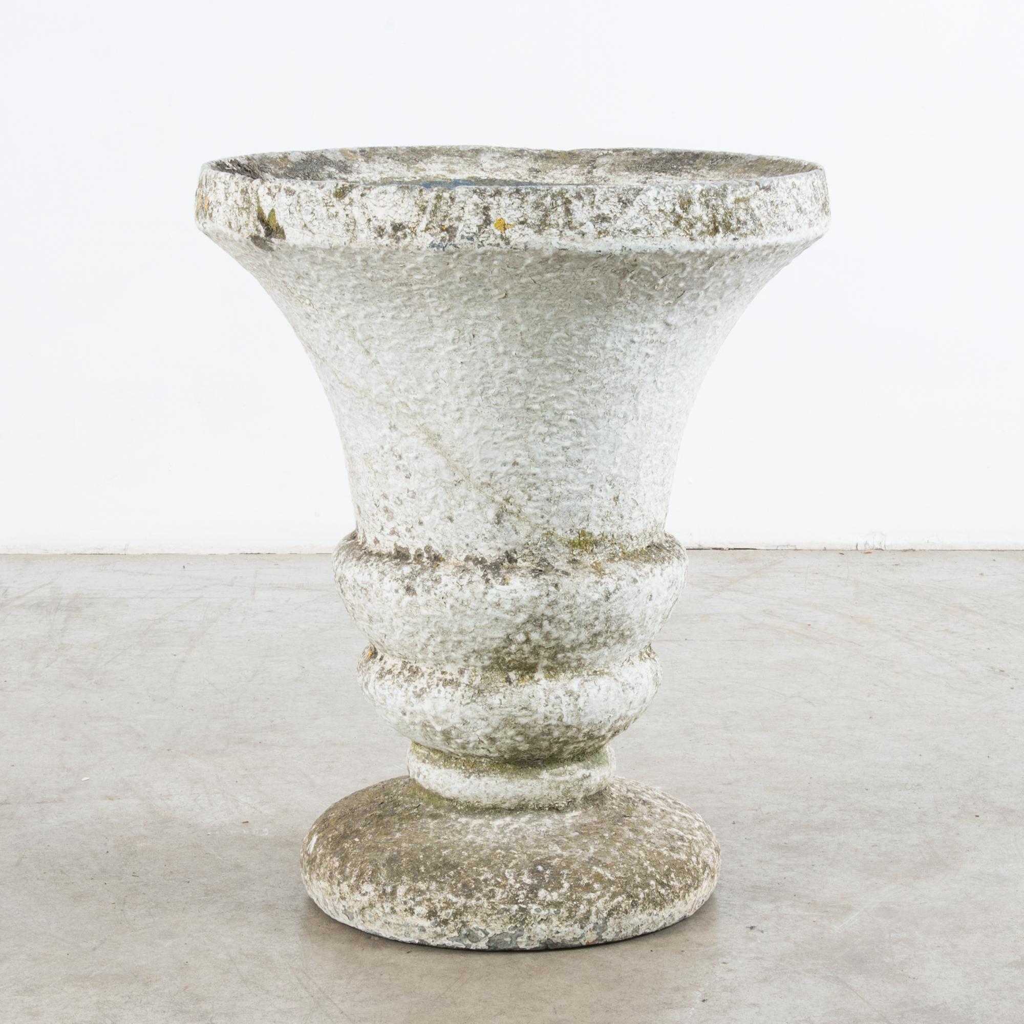 This bell-shaped concrete planter was made in France, circa 1960. With its rich, textured patina, the planter will inject an old-world charm into any interior space. The pair of ringed moldings above the circular base accentuates the curvilinear