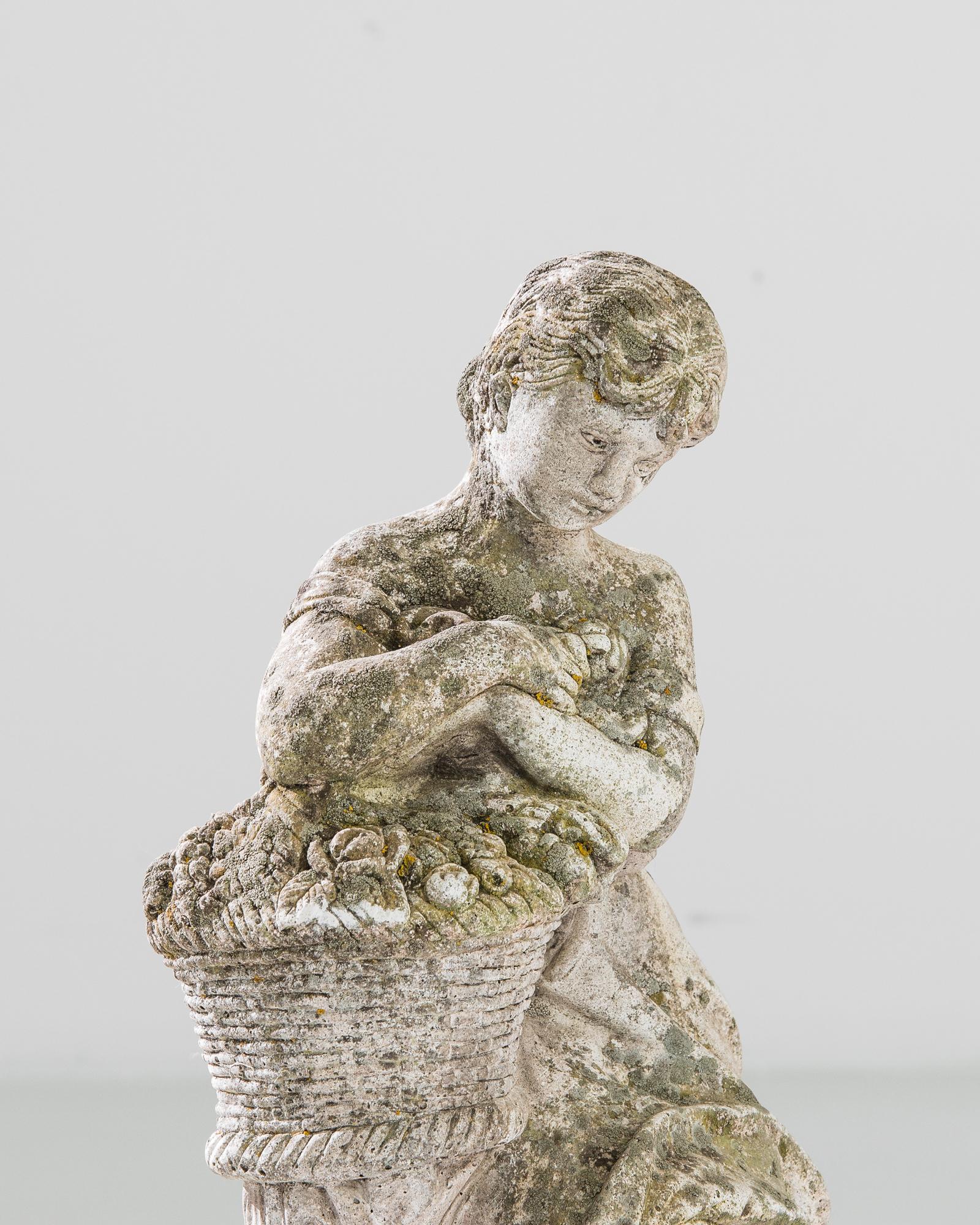 A concrete garden sculpture from France, produced circa 1960. Standing two feet tall on a circular base, this sculpture depicts a barefoot young woman wearing a dress and carrying a basket of fresh produce as she rests on a stump. Arms crossed,