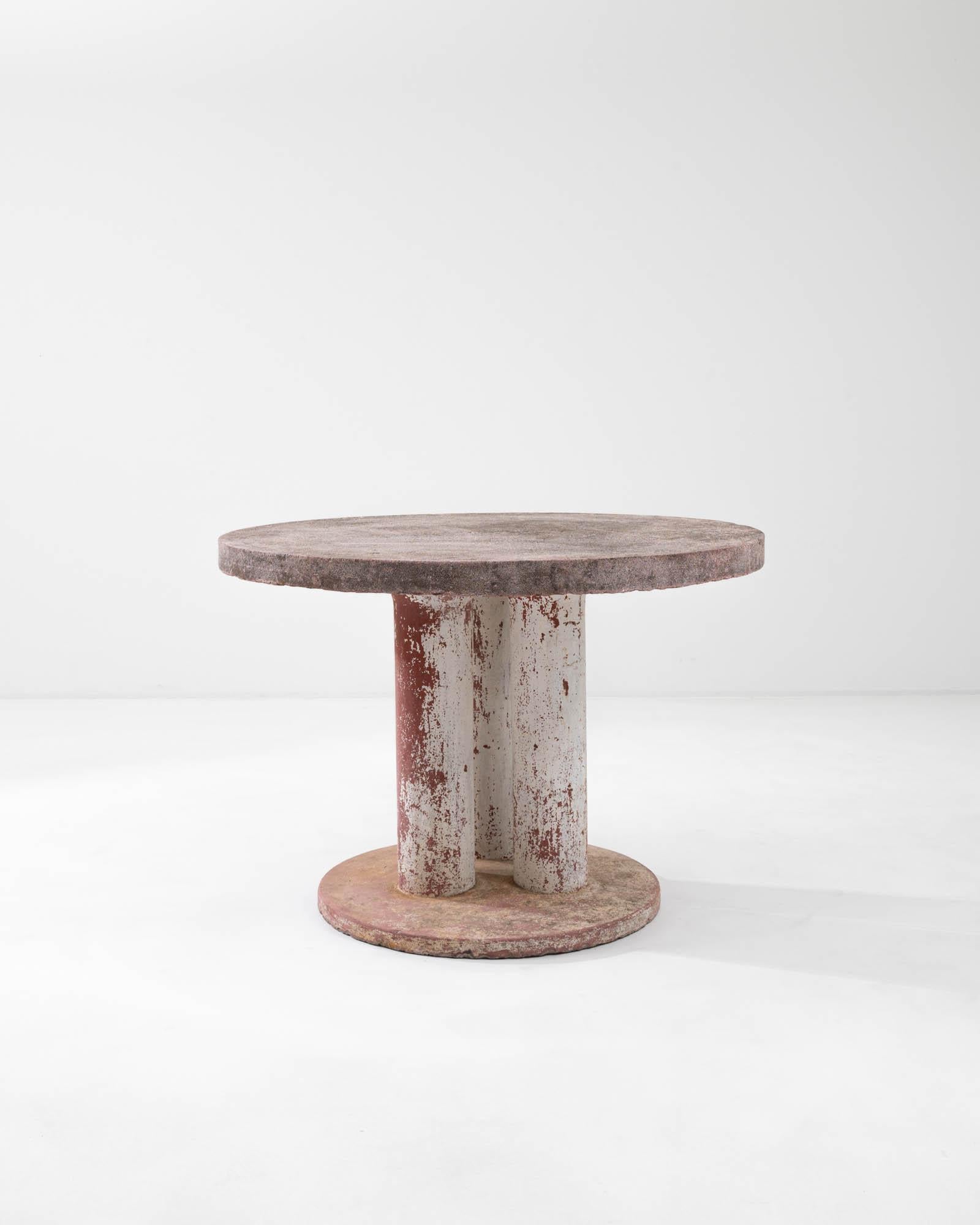 A concrete table created in 20th century France. Solid, sturdy, this monolithic furniture communicates a resilient withstanding of time. A minimal construction, three conjoined legs rise up from a smaller circular base to support a larger and