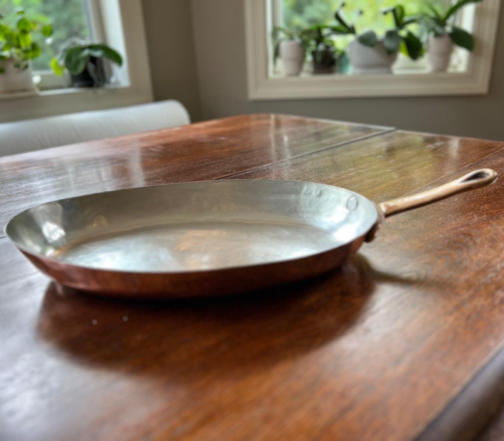 A a beautifully crafted vintage French copper gratin pan, ideal for roasting, gratins, or shallow frying. This pan showcases a timeless oval design with a heavy riveted brass handle, perfect for both professional and home kitchens. High-quality