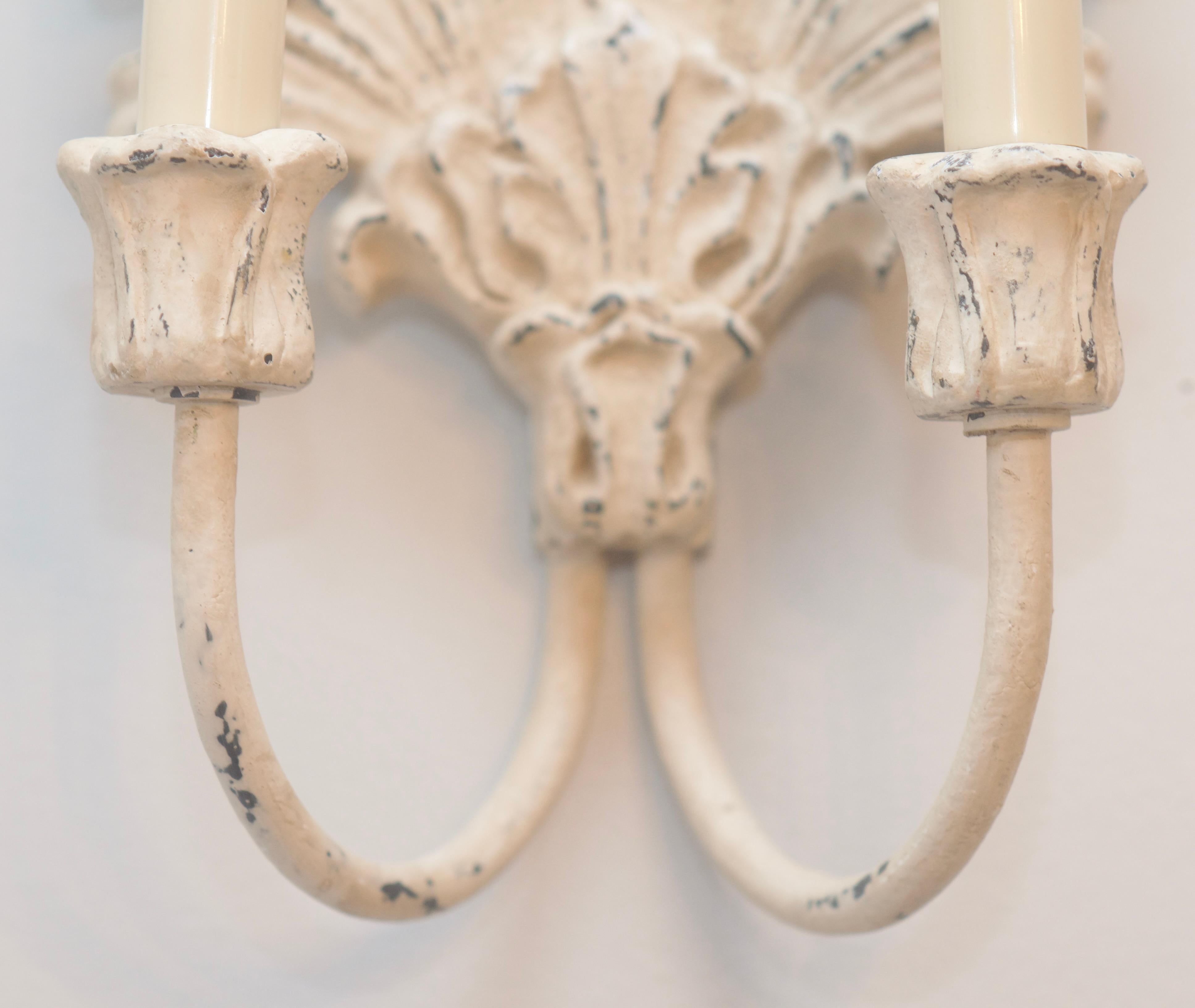 French Country Double Sconce in a sophisticated shell pattern.  Original finish includes cream paint over metal color with a natural distressed patina.  Set of two.  Each sconce has two arms.  Hardwired into the wall, these will make a beautiful