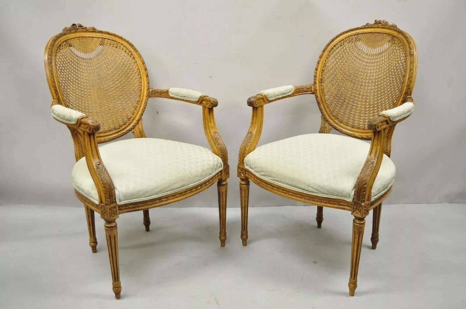 Vintage French Country Louis XVI Style Oval Cane Back Walnut Arm Chairs - a Pair. Cet article se caractérise par des dossiers en rotin avec un tissage orné sur le dessus des dossiers, des cadres en bois massif, un beau grain de bois, une finition