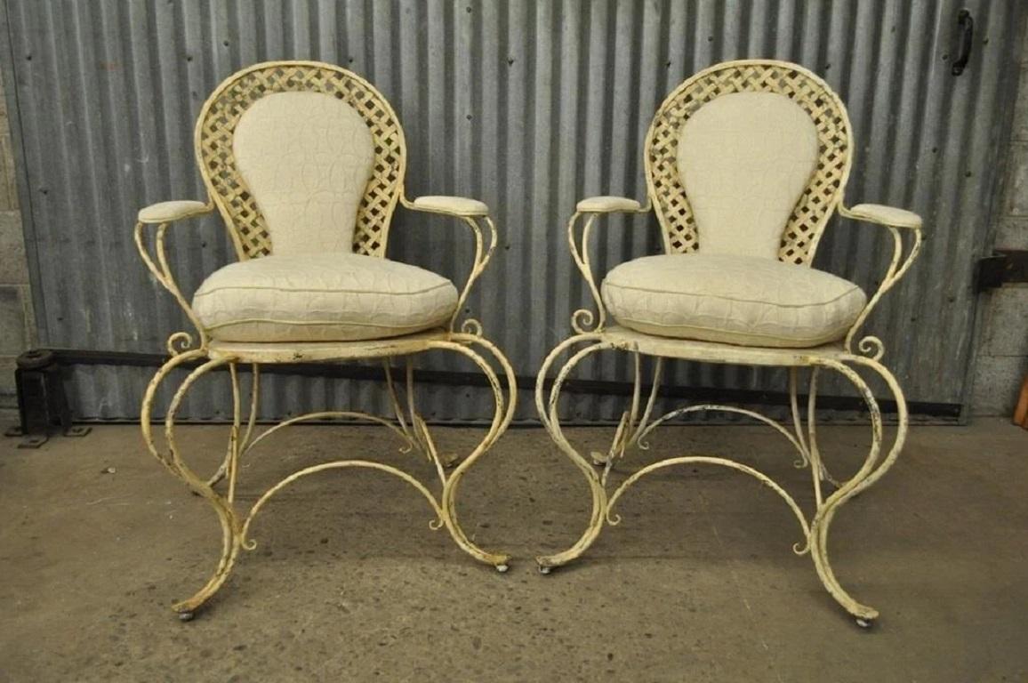 Chaises à accoudoirs vintage en fer forgé à enroulement de treillis (B) - Paire. Cet article se caractérise par une construction en fer robuste, des cadres fantaisistes, des bras et des pieds en forme de Curule, une finition peinte en détresse, des