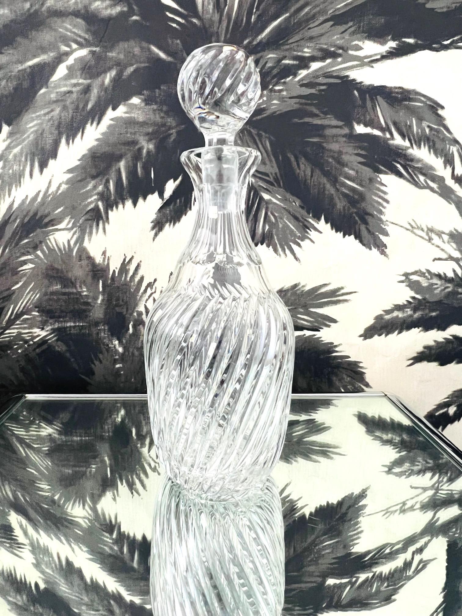 1970's blown glass decanter from France with matching round stopper. The stylized bottle has a tapered stem with faceted accents and has a bulbous base. It features elegant hand-cut swirls on a bias with a starburst etched base. Makes a chic
