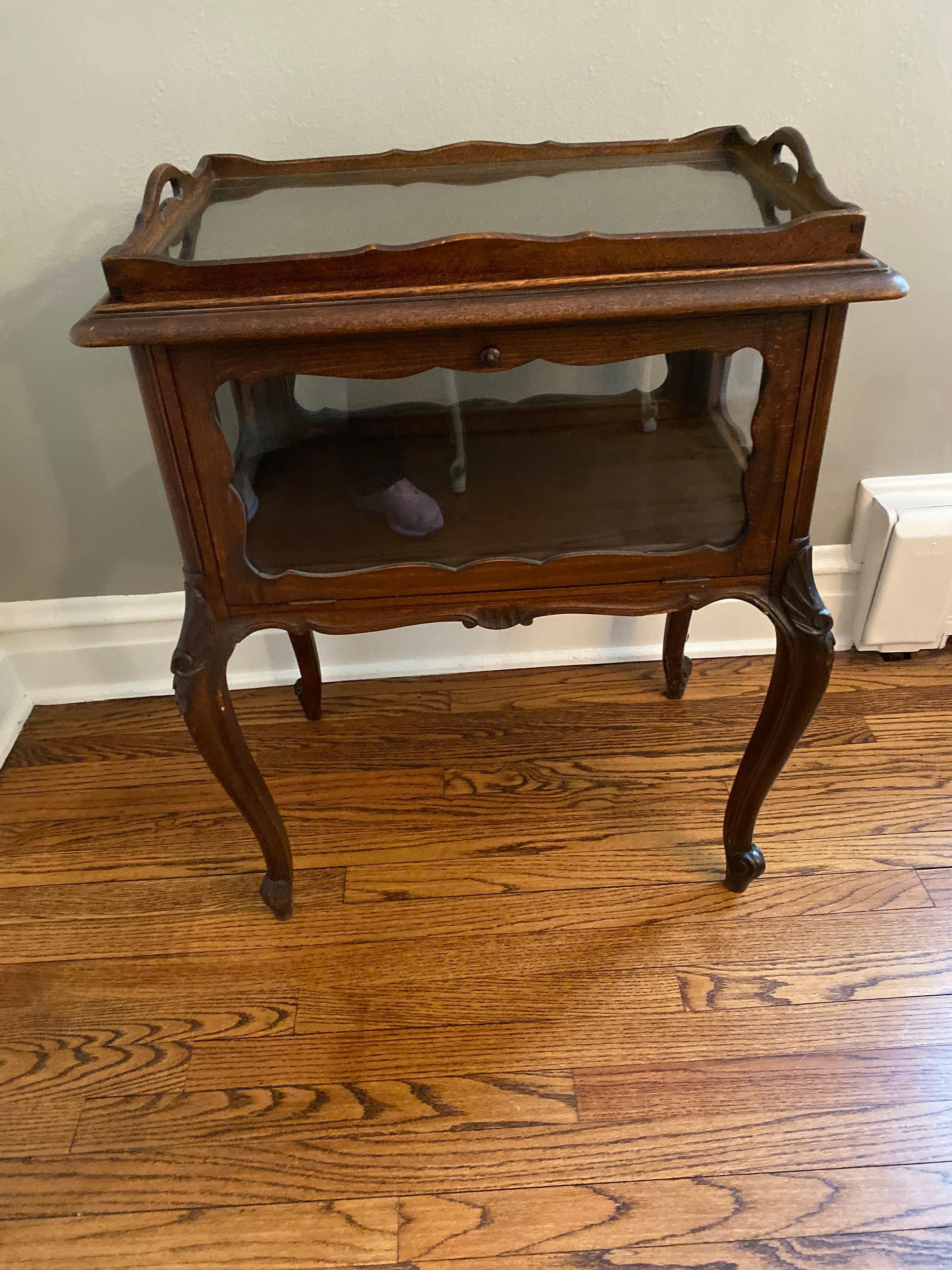 Solid mahogany... beveled glass panes, hinged door gives access to interior storage cabinet and removable glass serving tray. 
Wonderful carvings, delicately curved legs...

A wonderful piece we seldom see. It is extremely useful. The top glass