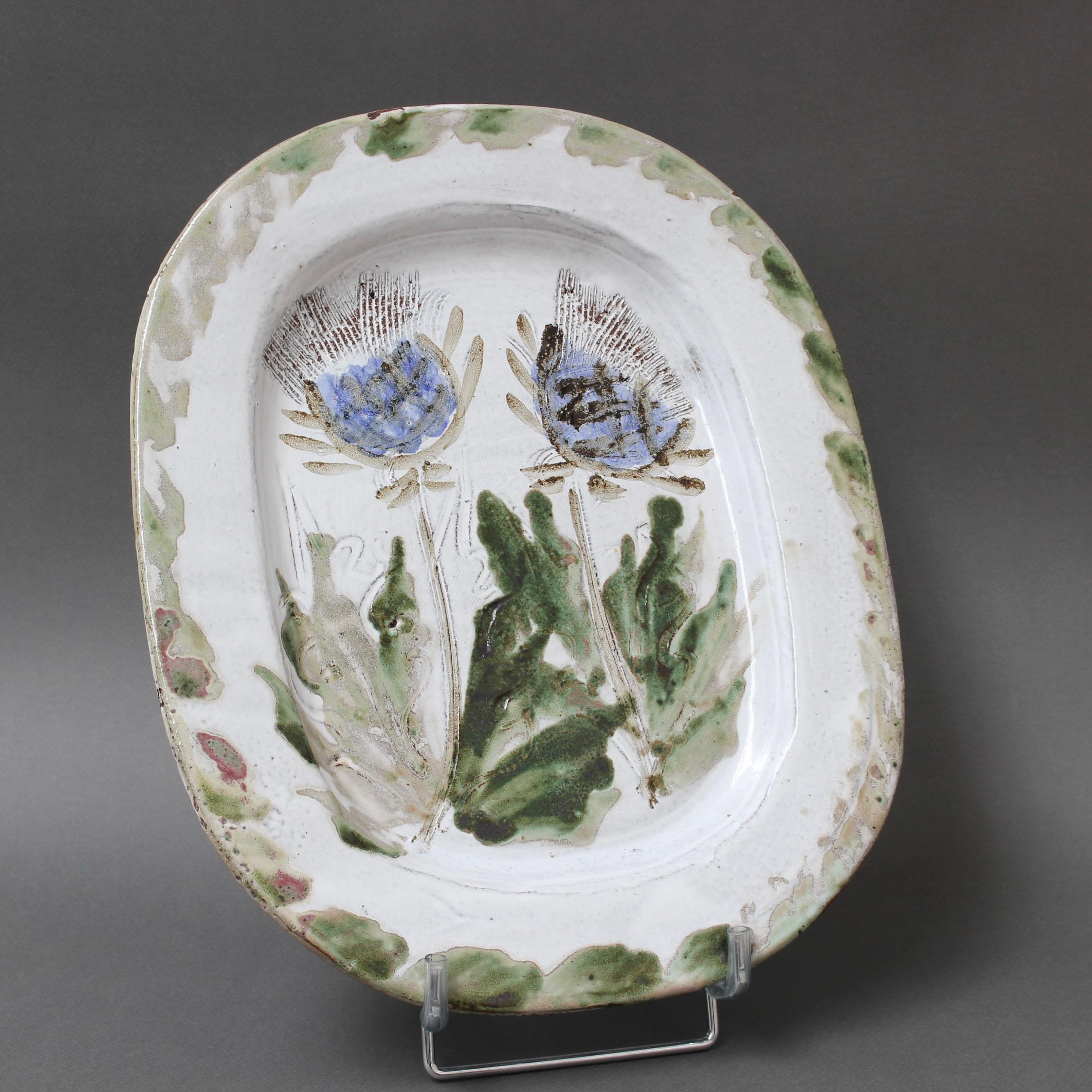 Midcentury decorative platter (circa 1970s) by Albert Thiry. A creamy-white glaze with touches of blue-grey provides the background for a colourful thistle motif in the centre recess. The rim assumes the colour of the flowers' foliage, some parts
