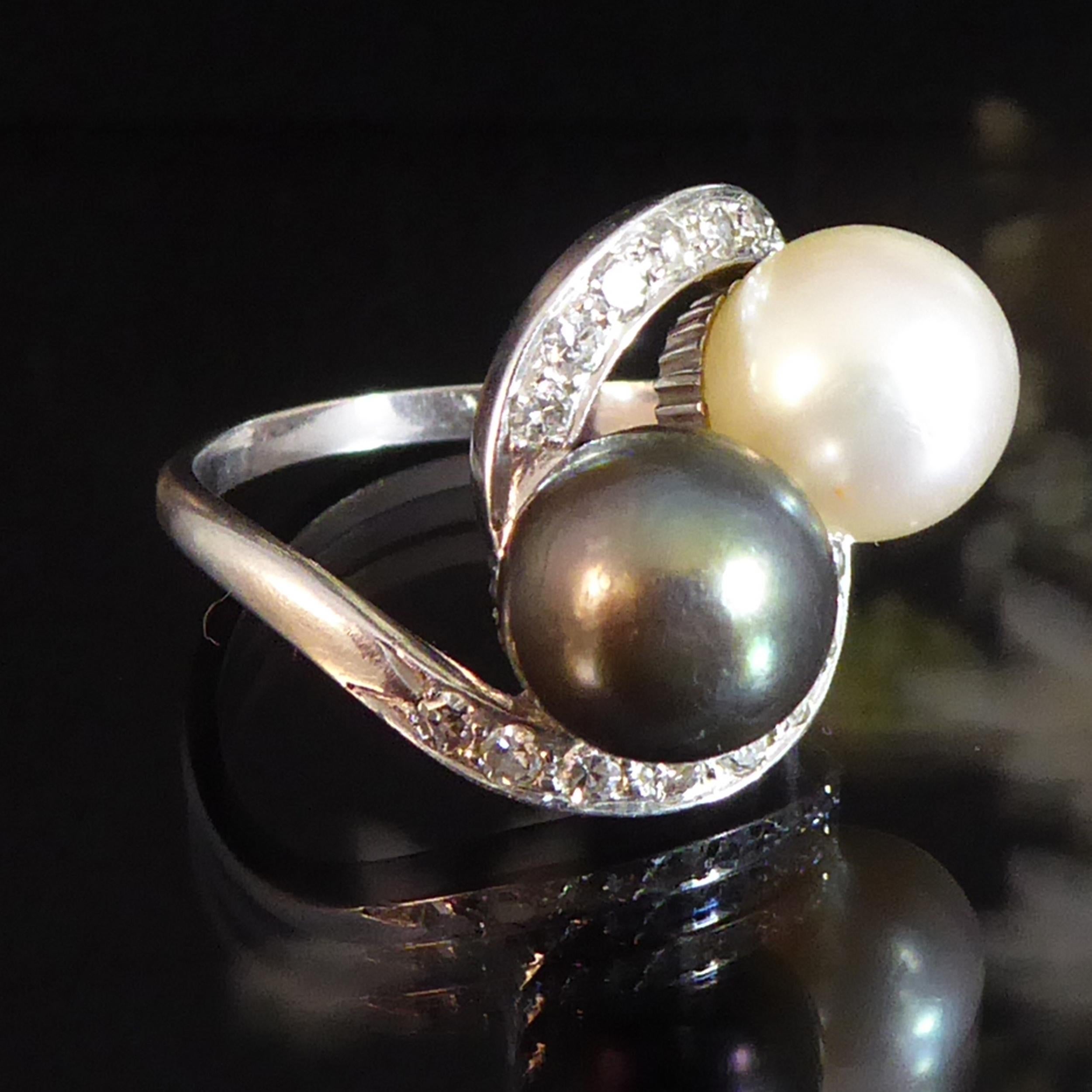 A vintage French design pearl and diamond cross-over twist ring giving a marvellous show on the hand.  Set with two principal pearls measuring 8.16mm and 833mm diameter, both assessed as Akoya, one in a cream colour with pink overtones the second