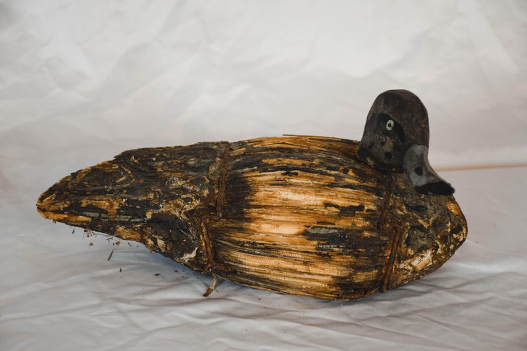 Found in France, this vintage duck decoy is truly a one of a kind find for the collector. The duck has been hand carved and covered in reed stalks held on by metal straps for a realistic look to attract live ducks. This piece would make a perfect
