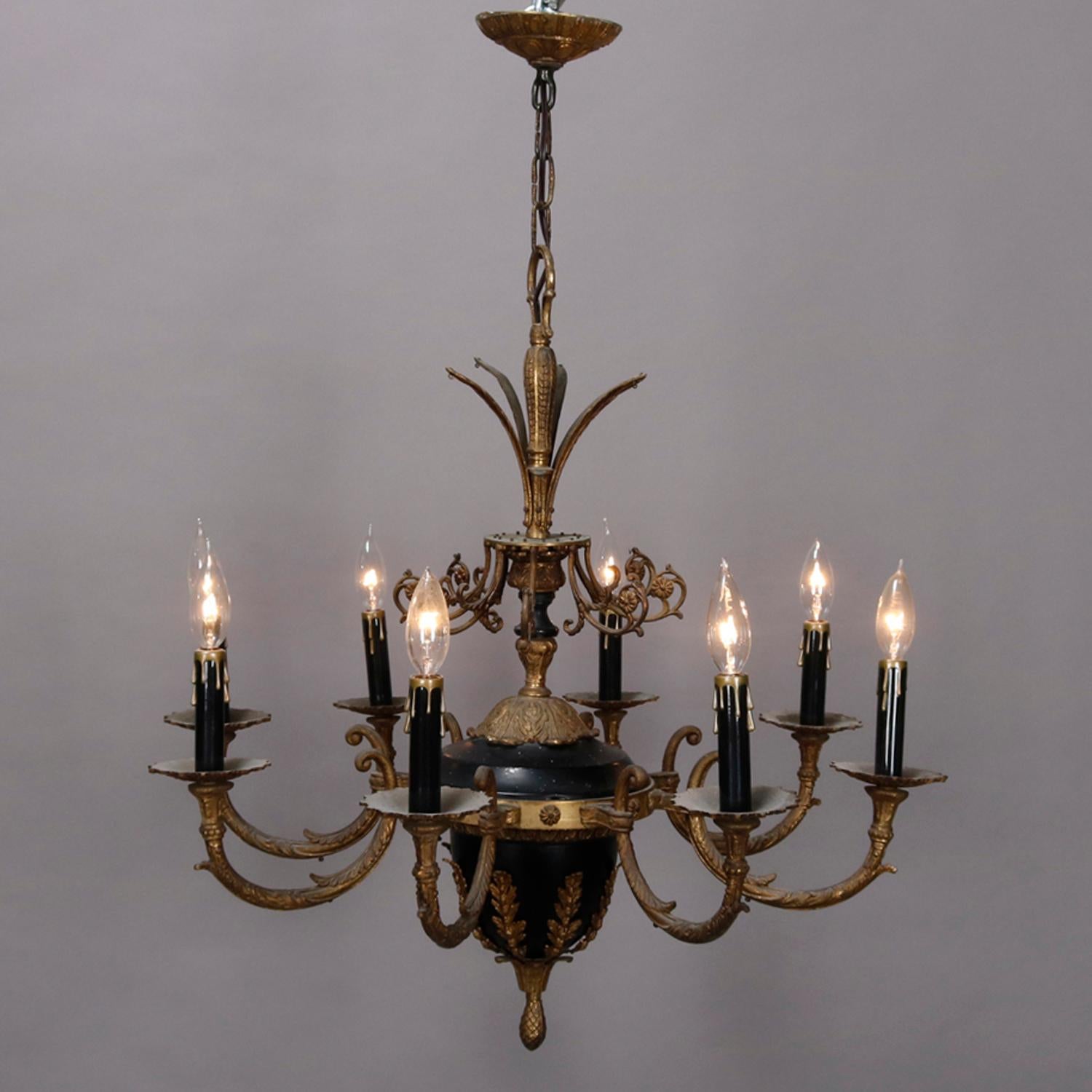 A vintage French Empire style chandelier offers gilt and ebonized metal frame with foliate crest surmounting urn form body having eight C-scroll foliate form arms terminating in drip candle lights, circa 1950

Measures: 29