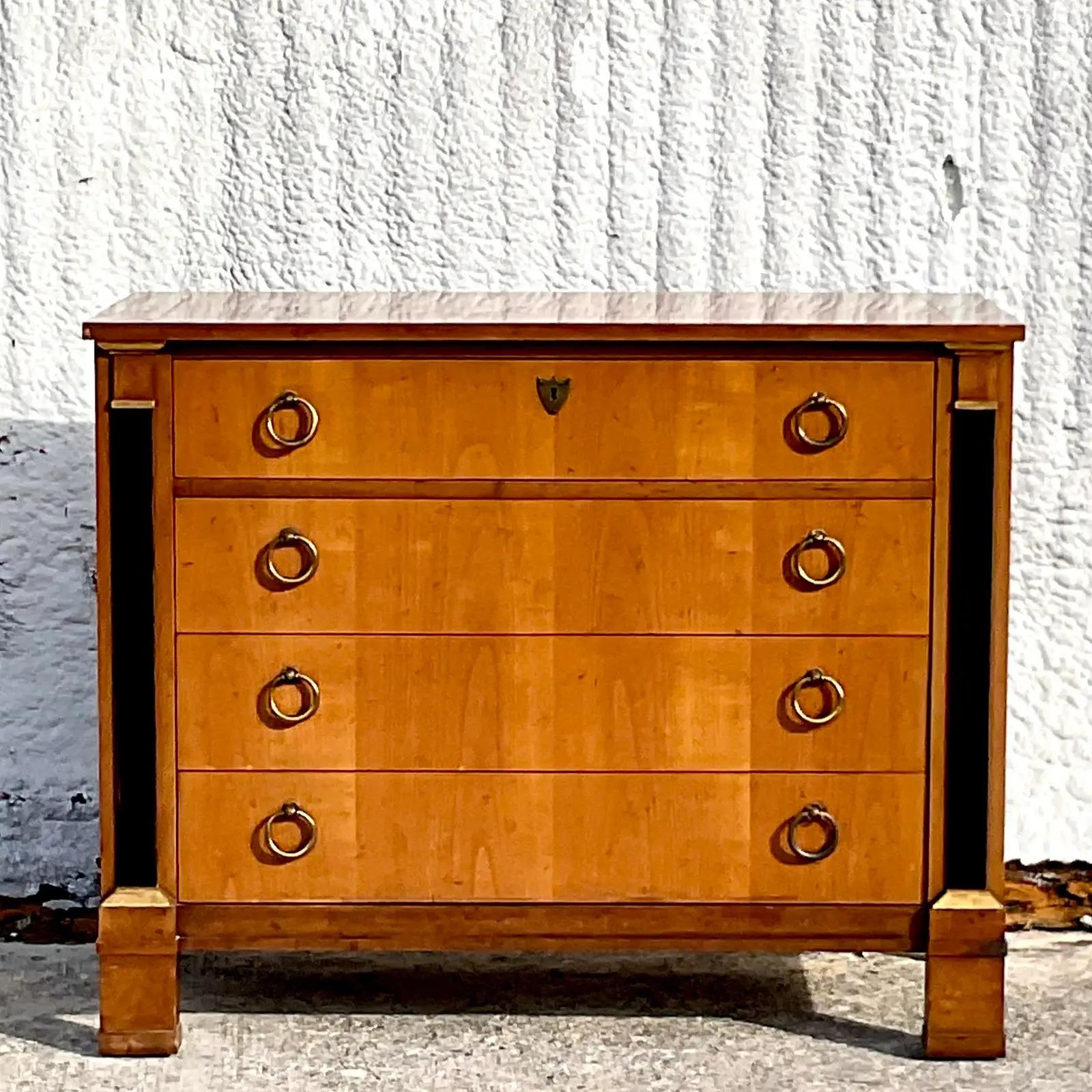 A fabulous vintage French Empire Neoclassical chest of drawers. Made by the iconic Baker Furniture group. Gorgeous wood grain detail and heavy brass hardware. Acquired from a Palm Beach estate.