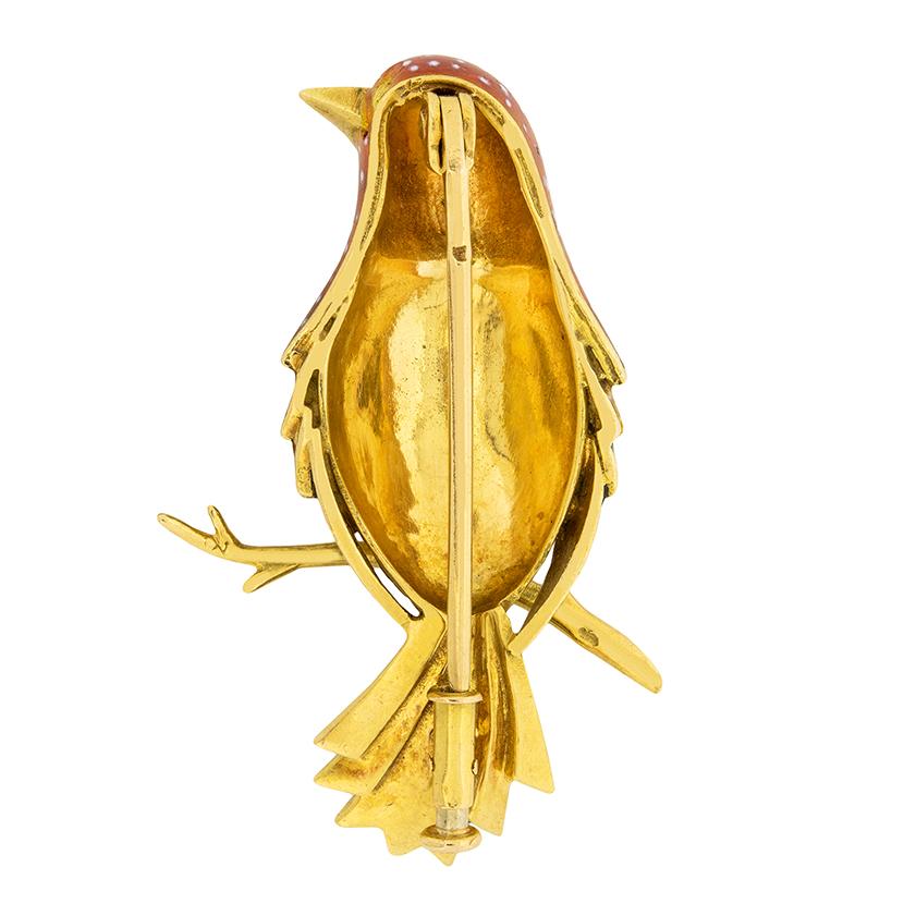 This fabulous 1940s bird brooch is beautifully enamelled. Great detail went into the white spotted enamel feathers, while the tail is a jet black enamel. The eye is a round cut 0.05 carat emerald, adding a colour contrast to the rusty colour of the