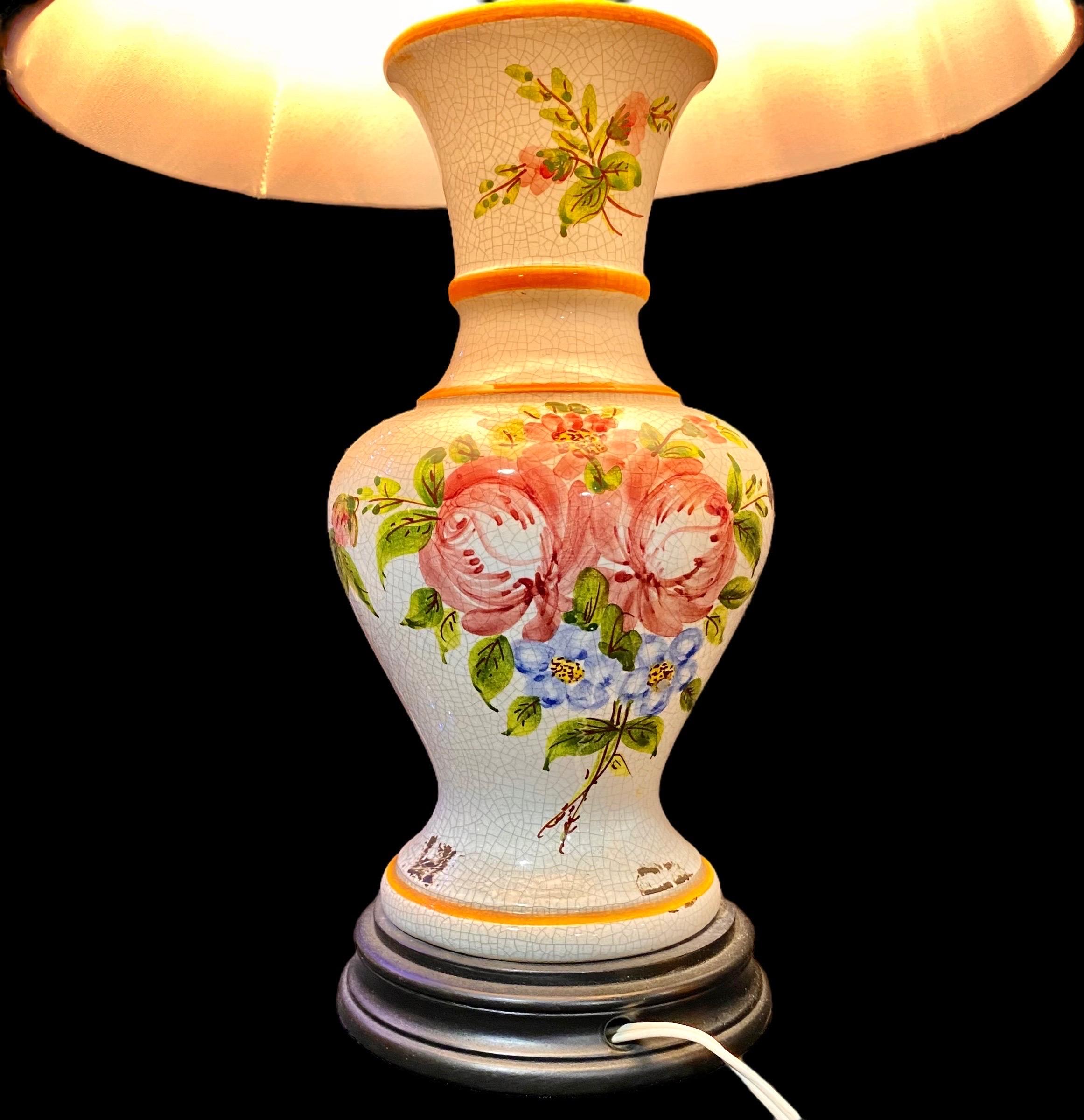 A vintage French faience vase turned table lamp with a lovely hand painted provincial floral design, wooden base and red silk shade. 