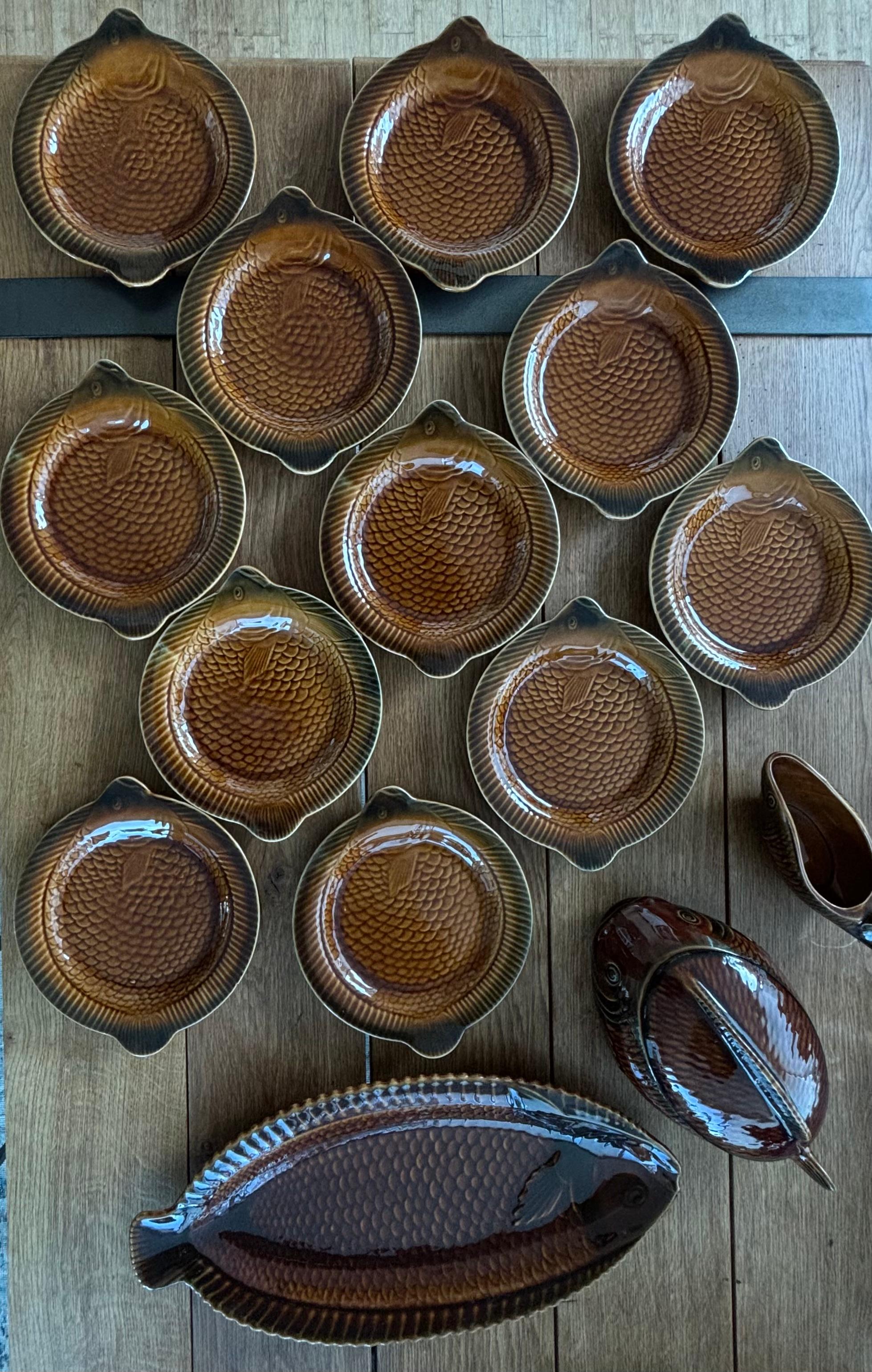 Très beau service à ragoût de poisson en céramique composé de 12 assiettes à dîner, d'une assiette de service, d'une saucière et d'une soupière. 

Dimensions : 
Assiettes à dîner de 24 cm de diamètre
Assiette de service 55 x 26 cm 
Saucière 25 x 8