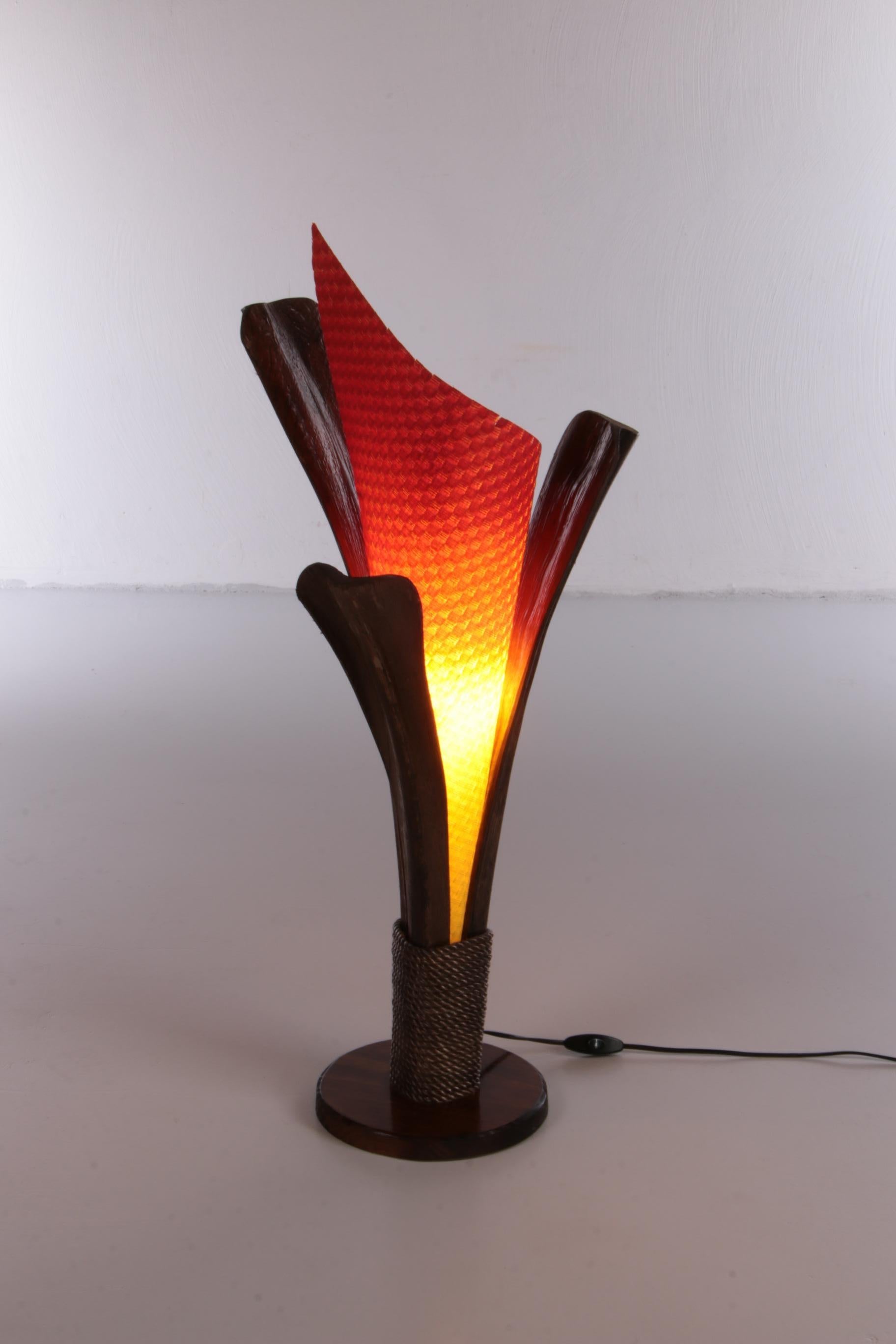 Beautiful vintage table lamp made in France in the 1980s.

The holder is made of dried palm tree bark, which gives the lamp a natural and rough look.

The lampshade is made of colored paper, which gives the impression of a flame. The lamp probably