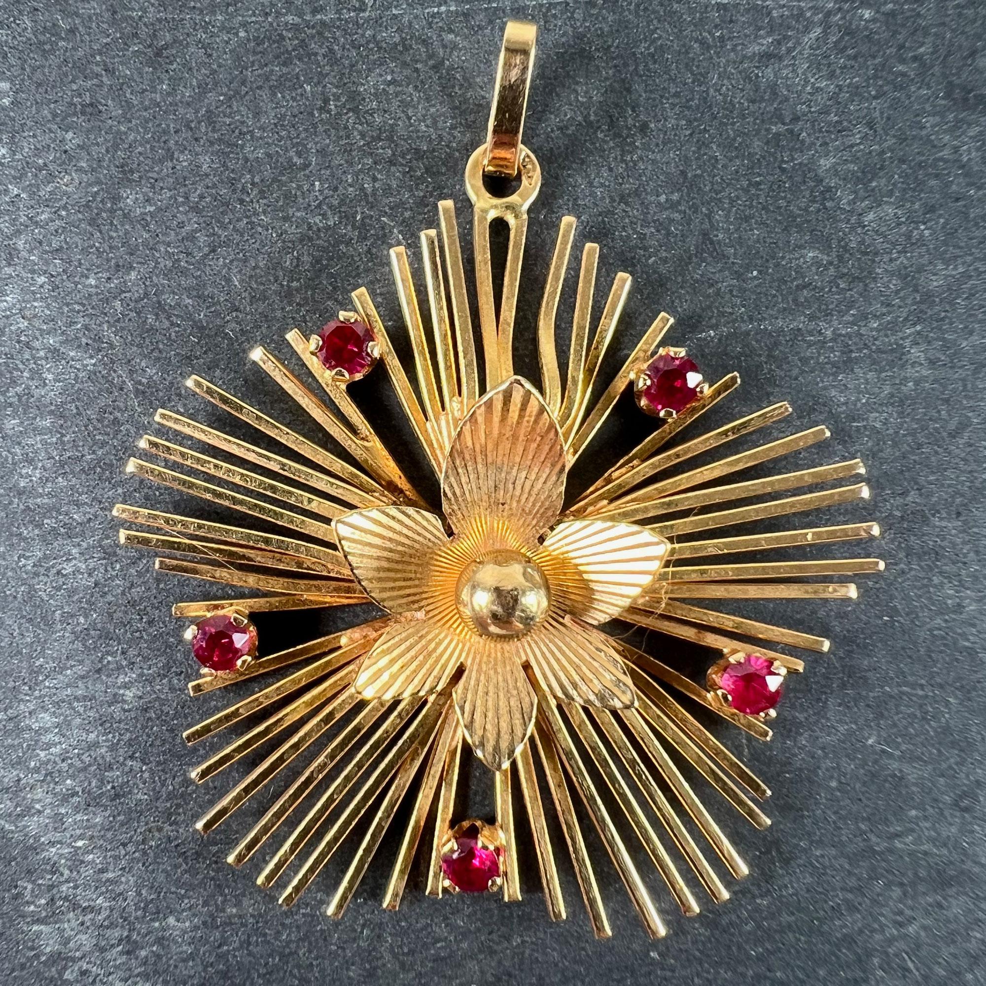 Pendentif vintage français en or jaune 18 carats (18K) conçu comme une fleur à six pétales avec un soleil rayonnant de fils d'or créant une forme à cinq pétales derrière elle, serti sur les fils avec cinq rubis synthétiques ronds de taille brillant