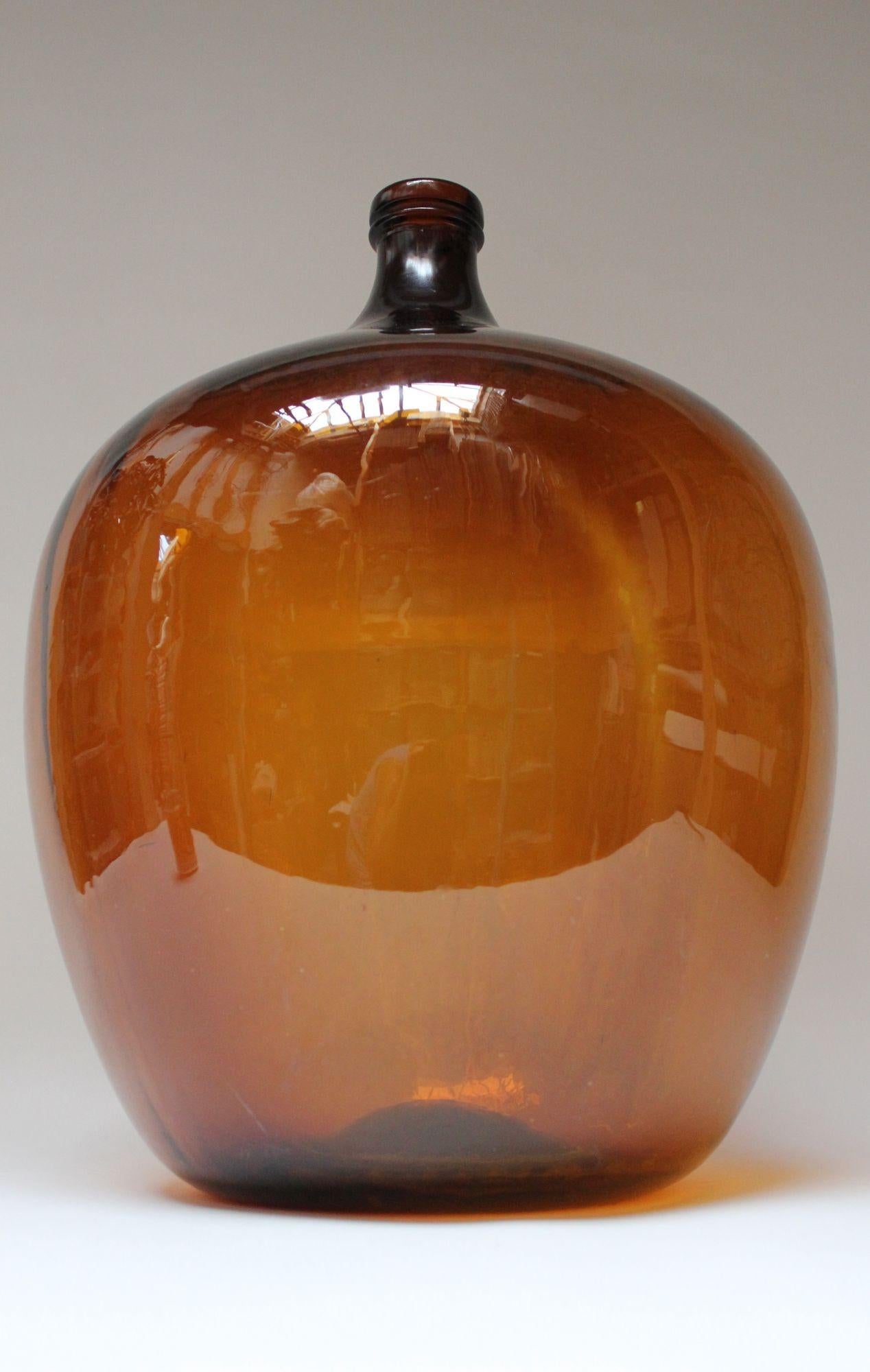 Impressive French Demijohn / Bonbonne Ambrée Brune originally used for transporting wine (ca. early 20th Century, France). Composed of 'blown-into-mold' amber glass exhibiting a smattering of bubbles within the glass itself. Unique color and