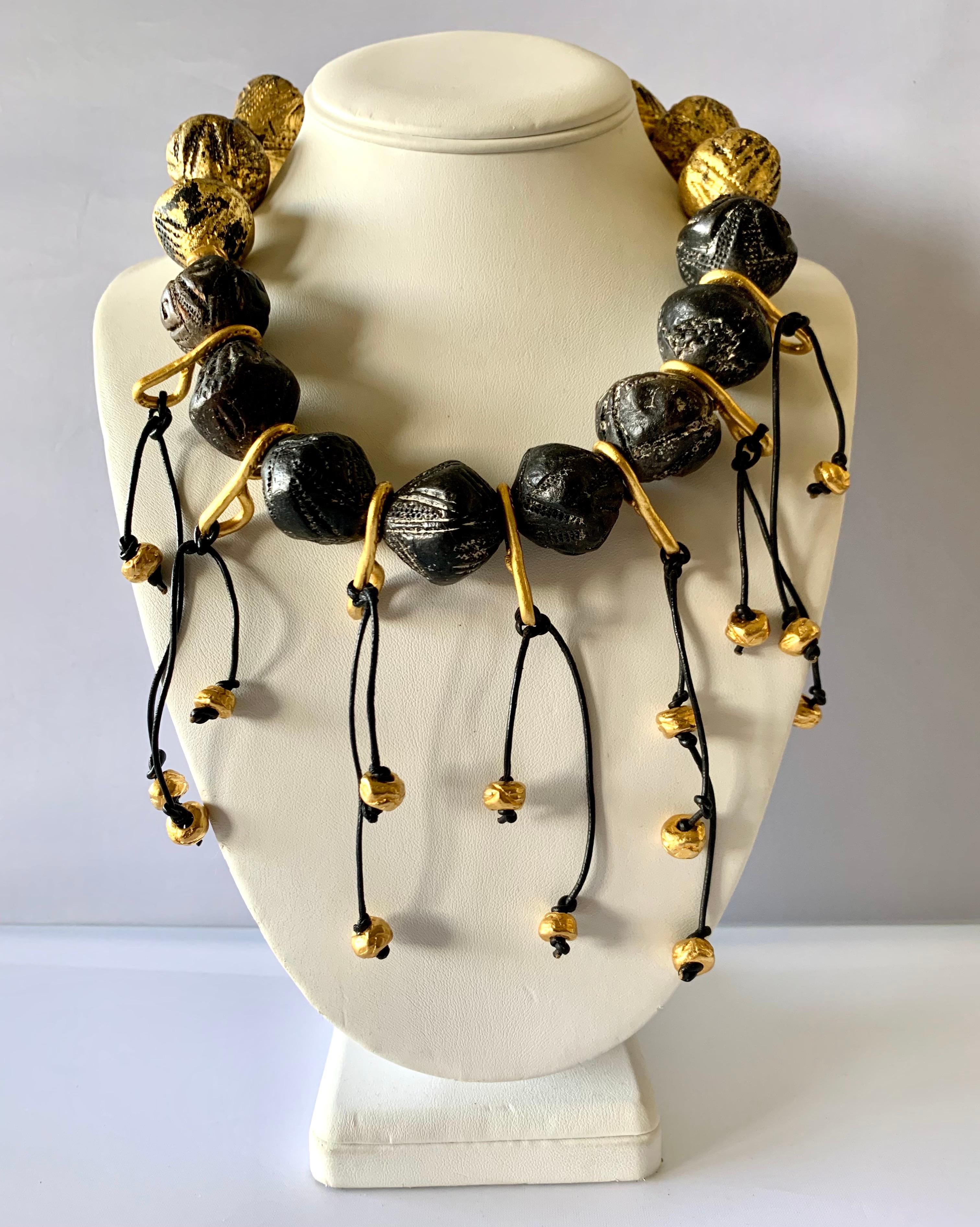 Vintage French oversized statement necklace, comprised out of hand-carved stone beads depicting tribal motifs. Black leather fringe tassels with gold beads give the necklace extra drama -  made in France circa 1980/90 by Pascal.