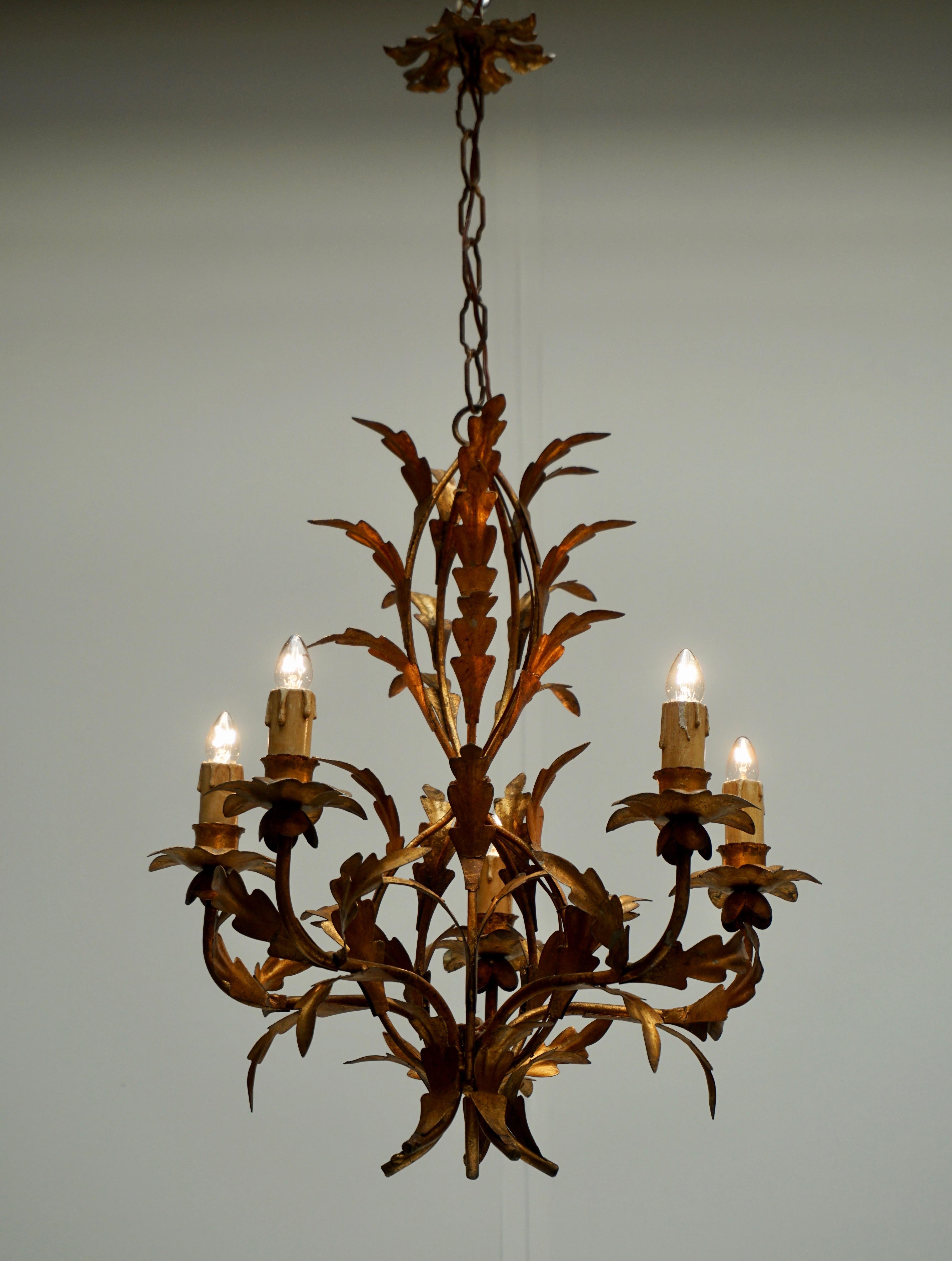 A fabulous vintage French tôle chandelier of gilded iron in the form of a lavish bouquet of lilies and leaves and stems from France circa 1940 with ten lights. This gorgeous chandelier is modeled after the famous fixtures created of painted metal