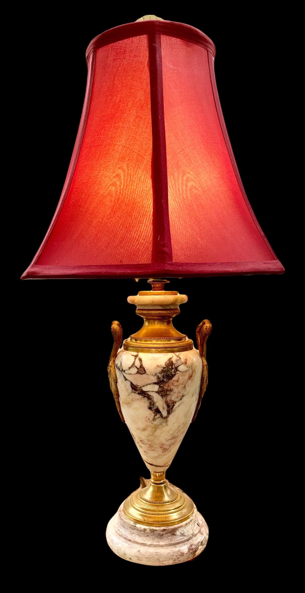 A lovely petite, vintage French figured marble and gilt bronze table lamp with a new red moire shade, having beautiful ormolu mounts, decorative guilded and beaded feet and decorative guilded caps. 
Perfect in a dressing area, on a vanity, in a