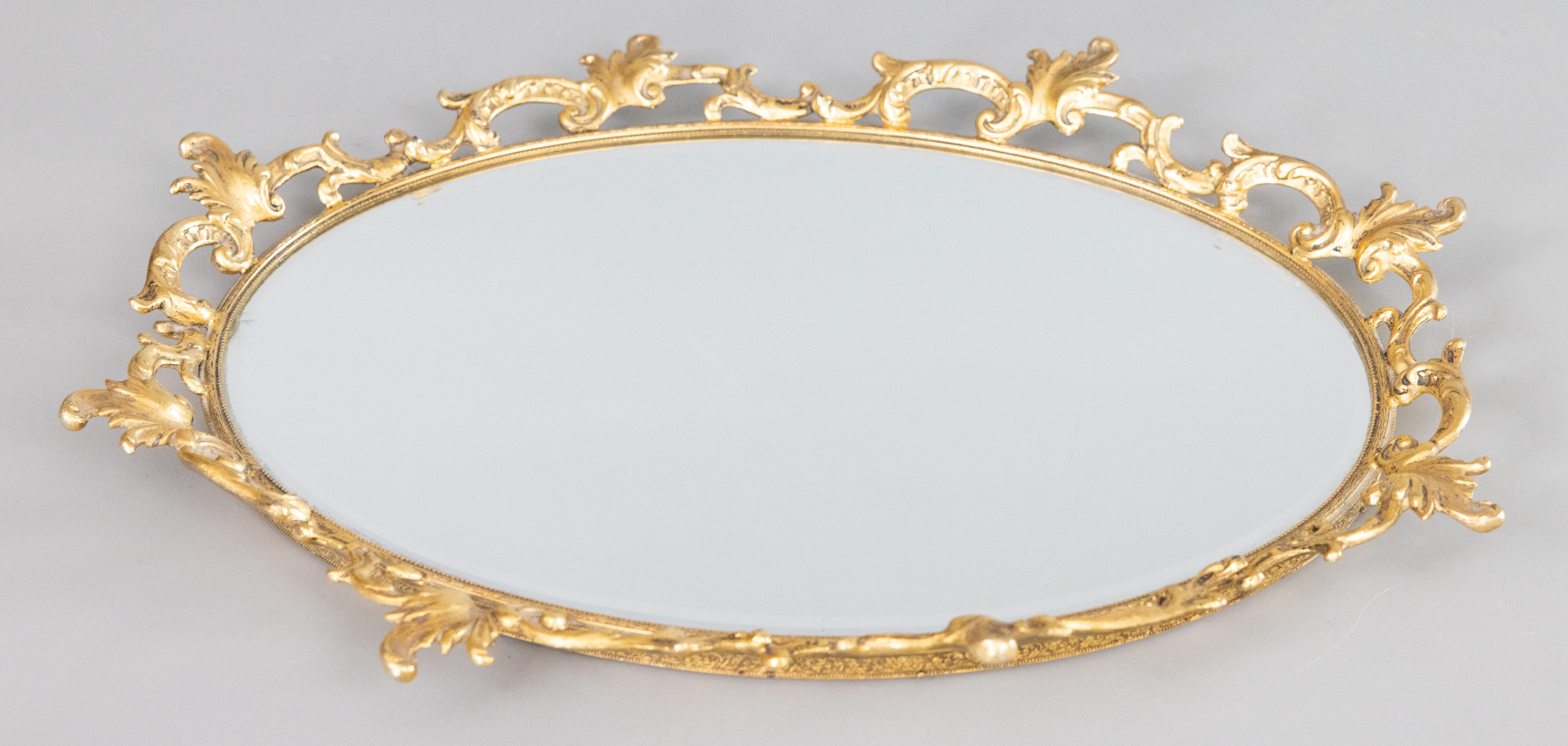 A stunning vintage French gilt ormolu oval mirror vanity or bar tray, circa 1950. This beautiful tray is a nice large oval size surrounded by a gorgeous scrolling acanthus leaf gallery in a lovely gilt patina. It would be perfect for displaying your