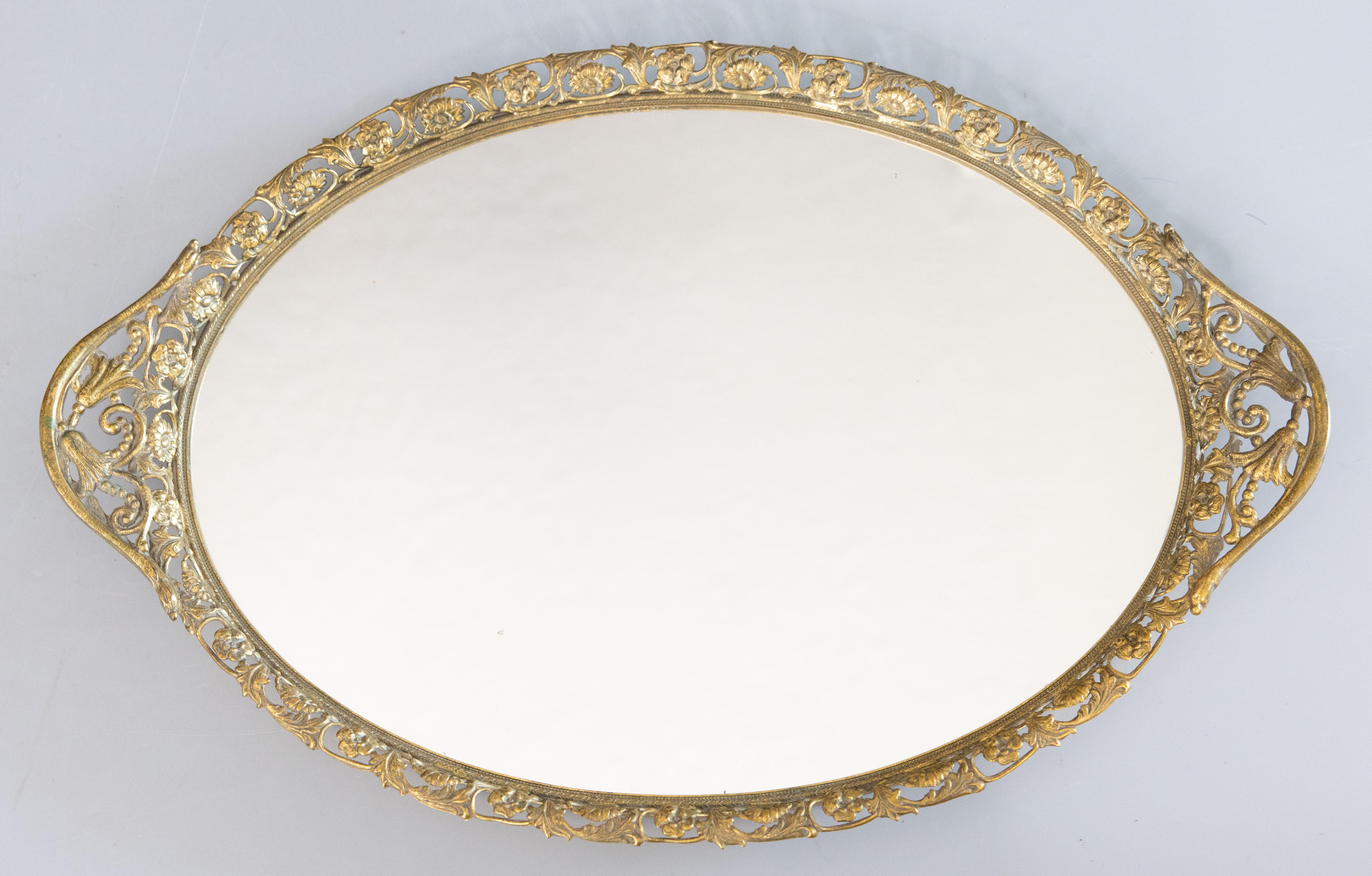 Superbe plateau de bar ou de vanité à miroir ovale en bronze doré, vers 1950. Ce magnifique plateau est d'une belle taille ovale entouré d'une magnifique galerie florale avec des poignées ornées dans une belle patine dorée. Il serait parfait pour