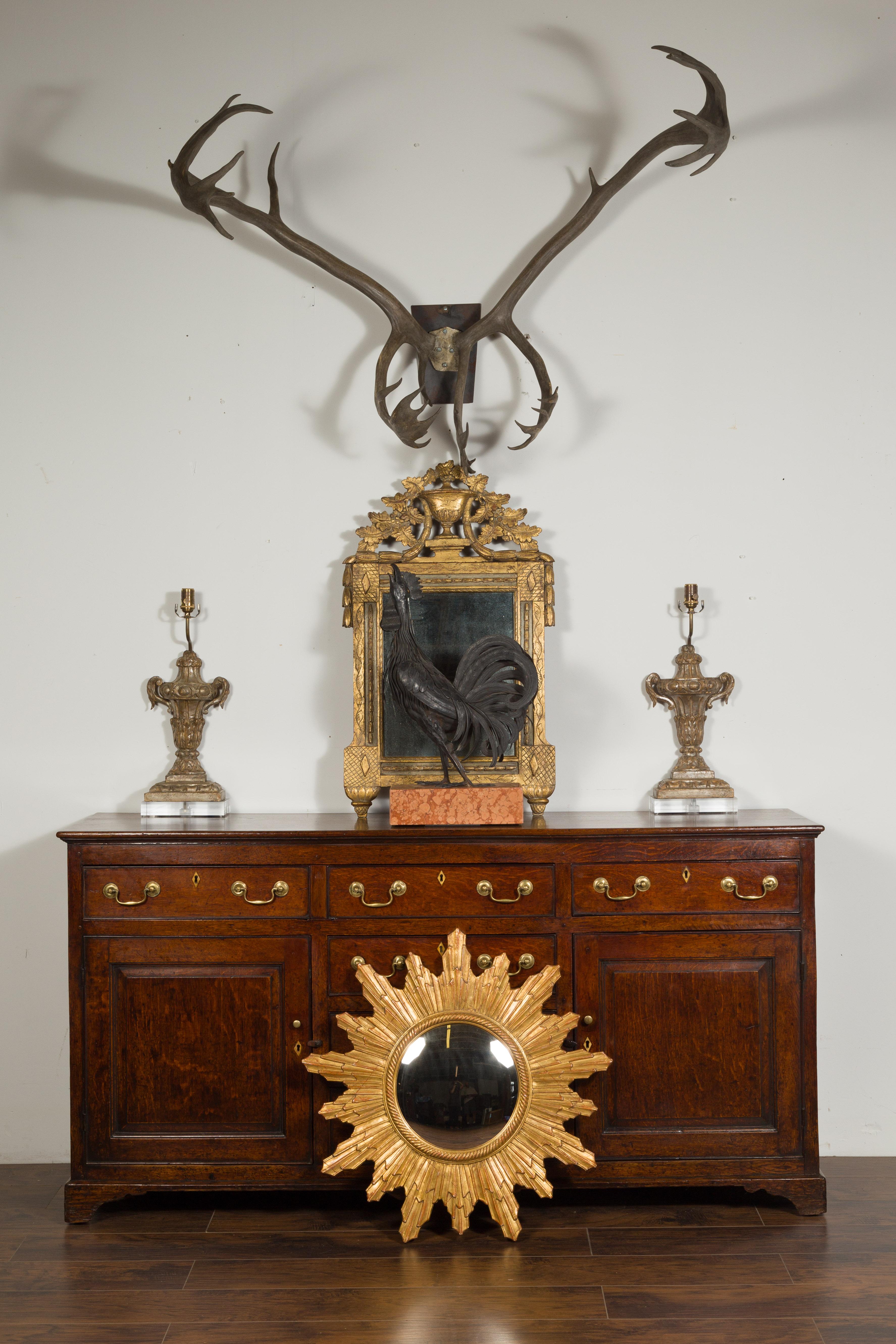 A French vintage gilt sunburst from the mid-20th century, with rays of varying sizes and convex mirror. Born in France during the 1960s-1970s, this sunburst features a convex mirror plate surrounded by a twisted inner molding, from which are