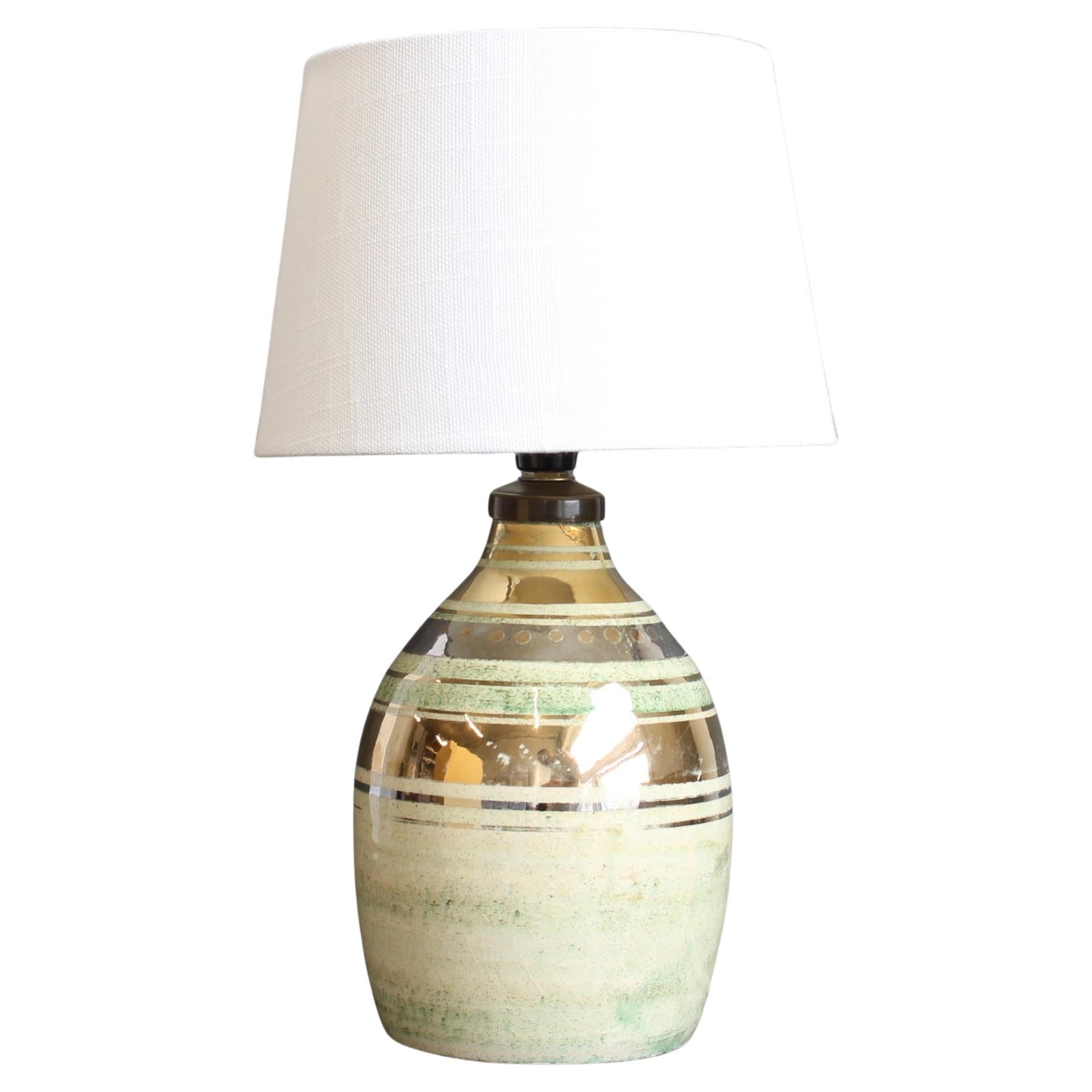 Élégante lampe de table en céramique de Georges Pelletier pour La Roue, fabriquée à Vallauris dans les années 1970. La lampe présente une silhouette raffinée en forme de bouteille avec une surface émaillée lustrée qui mélange des tons verts sauge