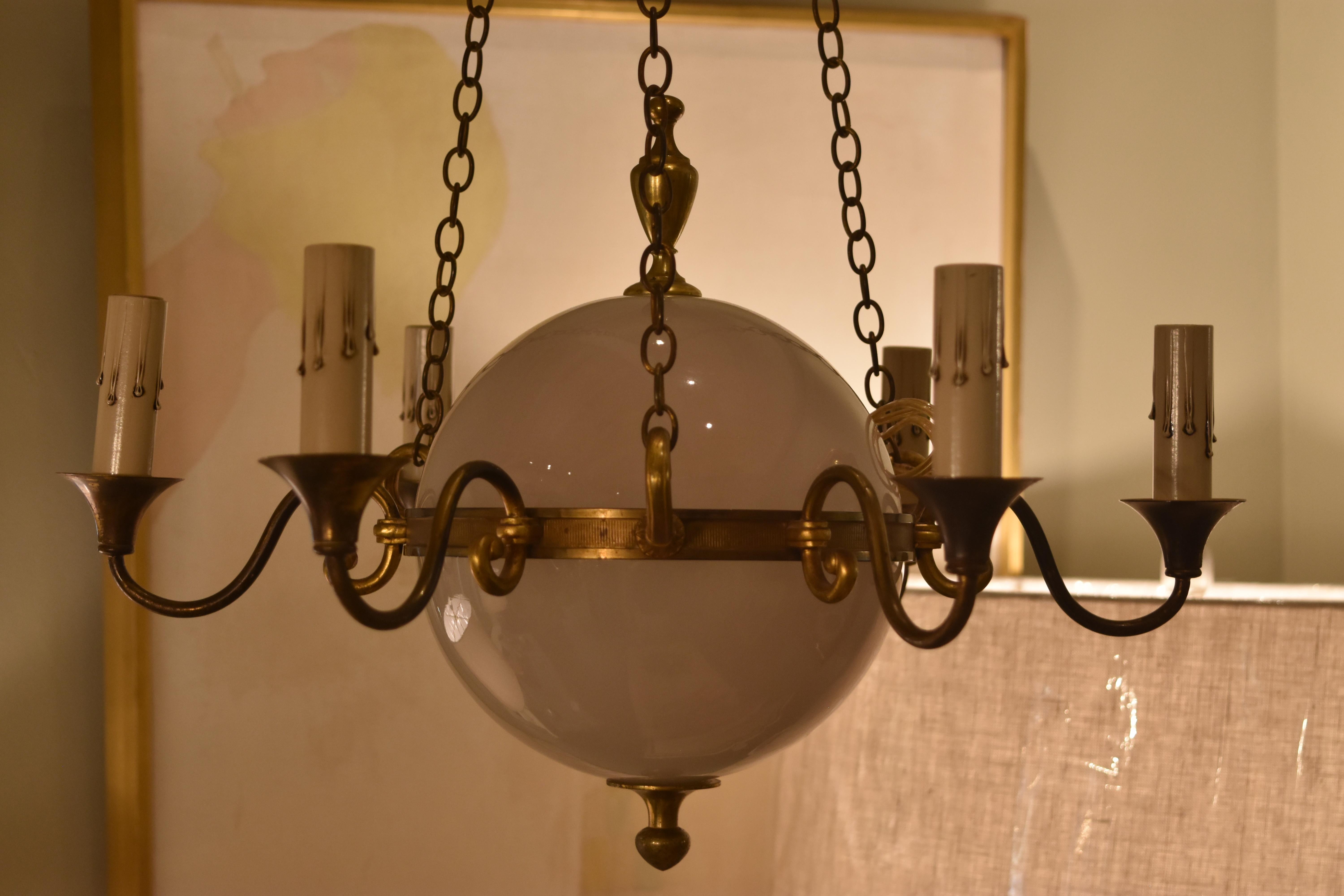 This small vintage French six-arm chandelier features a white glass globe surrounded by six scrolling arms and hanging from three chains. It has been newly rewired for American use.