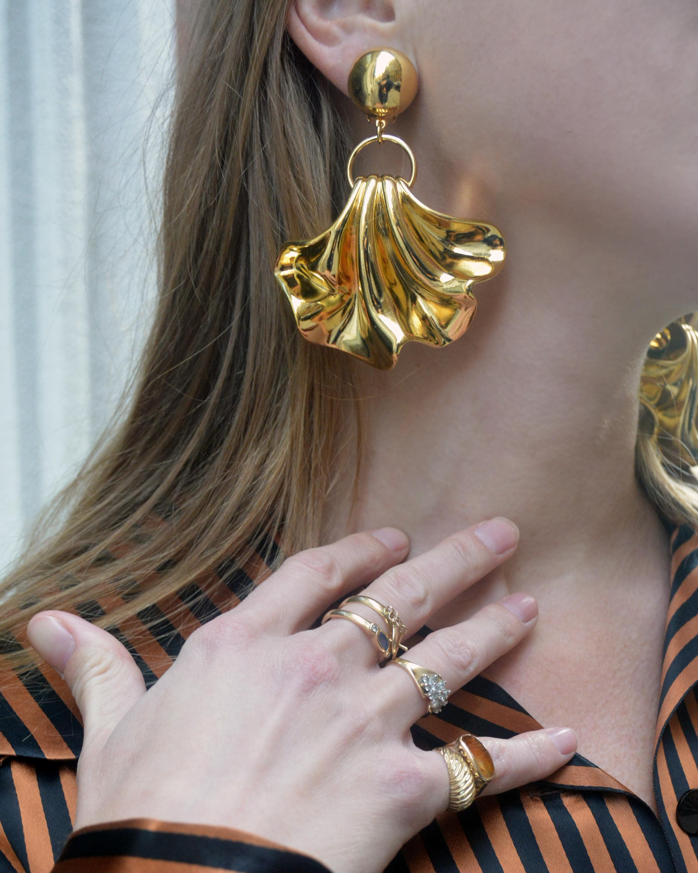 Fabriquées en France, ces boucles d'oreilles vintage à déclaration sont un look qui définit la tenue. Le pendentif doré en forme d'éventail a une forme ondulée et organique, avec beaucoup de mouvement lorsqu'il se balance librement de l'anneau en