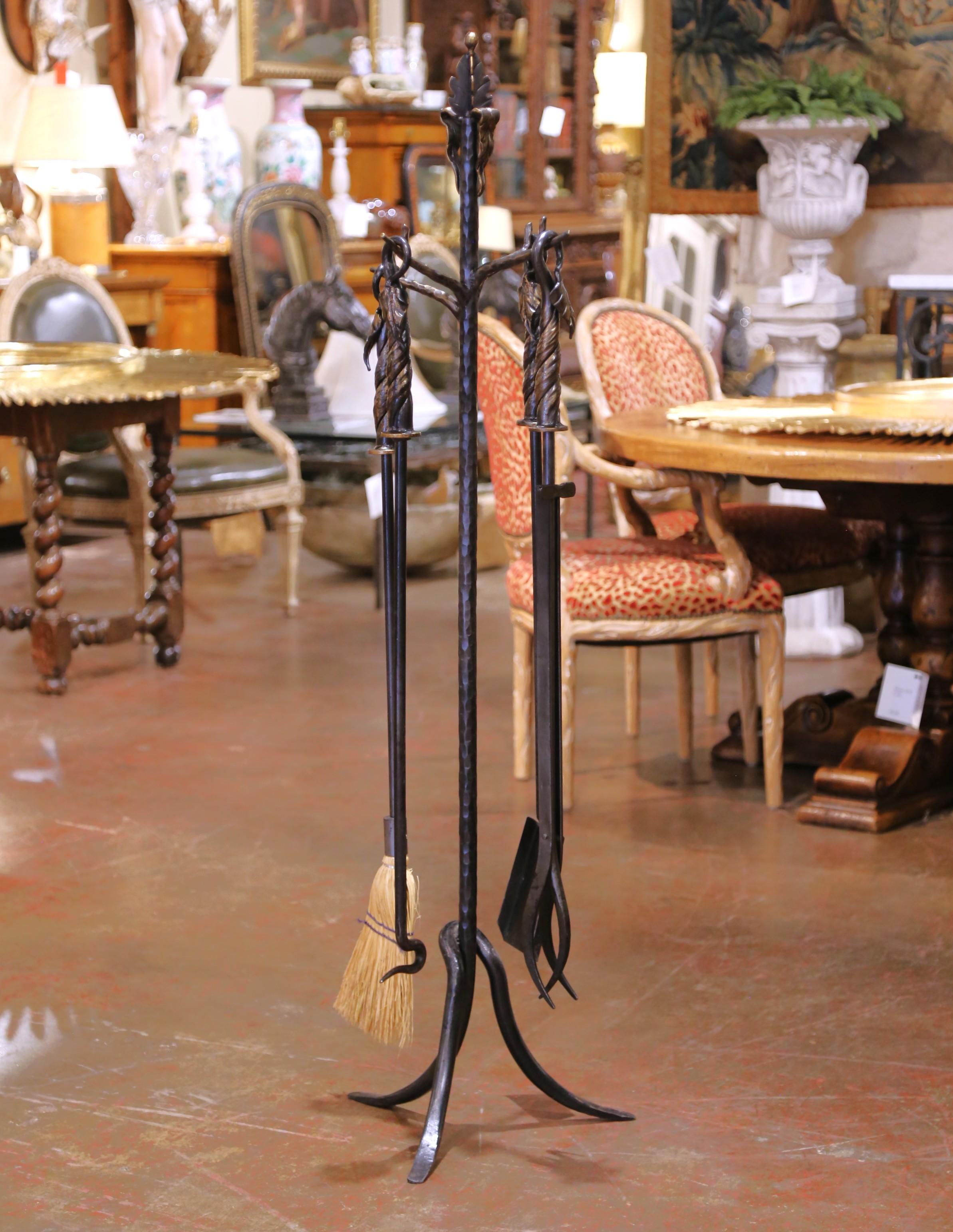 Questo set di attrezzi da camino gotico francese vintage, noto come Serviteur, è stato realizzato in ferro battuto a metà del XX secolo. Il set è composto da cinque elementi: un supporto alto e quattro strumenti: attizzatoio, pinze, spazzola e pala,
