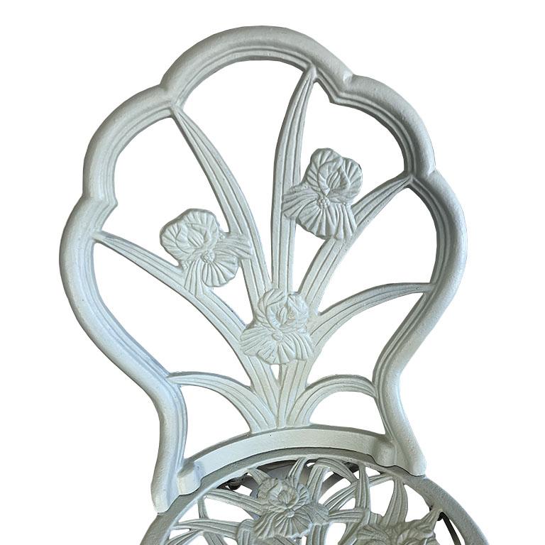 Verleihen Sie Ihrem Außenbereich einen Hauch von zeitloser Romantik mit diesem Bistro-Set aus Gusseisen im Vintage-Stil, bestehend aus zwei verzierten Stühlen und einem passenden runden Tisch mit Glasaufsatz. Das im traditionellen französischen