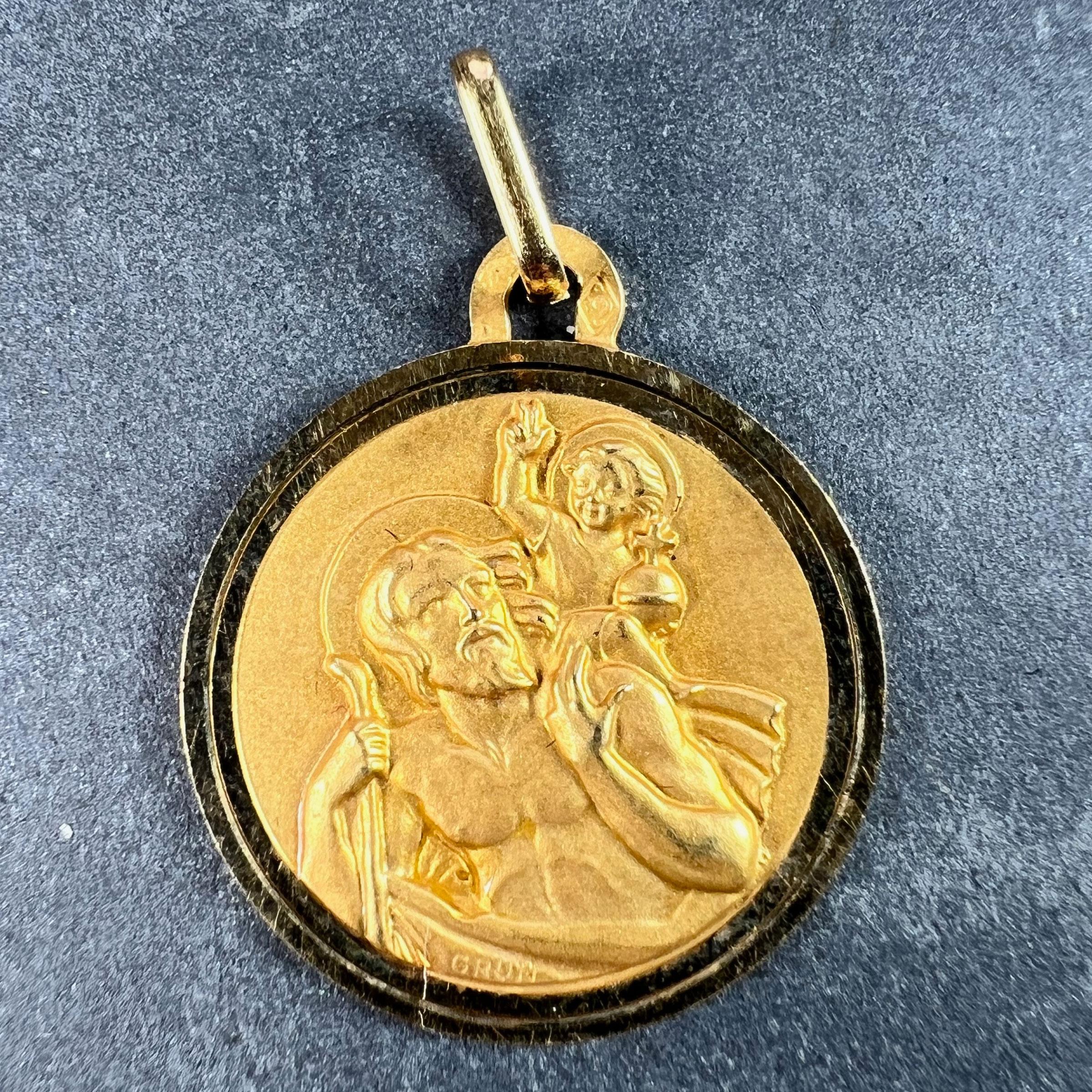 A French 18 karat (18K) yellow gold charm pendant depicting St Christopher as he carries the infant Christ across a river. Signed Grun. Stamped with the eagle’s head for French manufacture and 18 karat gold, and maker’s mark for Perroud. The