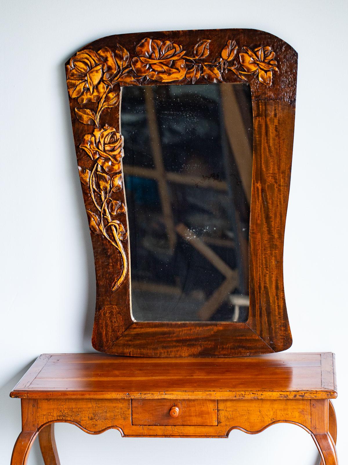 This vintage French Art Nouveau period mirror circa 1910 features an asymmetrical arrangement of hand carved climbing roses. The unique shape of the mirror reflects the Art Nouveau aesthetic of asymmetry and a fascination with natural forms. Please