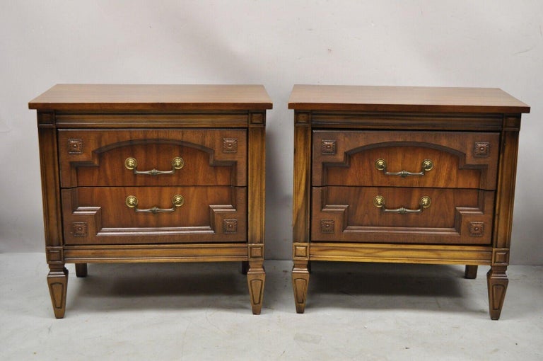 Vintage French Hollywood Regency style 2 drawer nightstand bedside tables - a pair. Item features a beautiful wood grain, nicely carved details, 2 drawers, tapered legs, very nice vintage pair. Circa Mid 20th Century. Measurements: 24.5