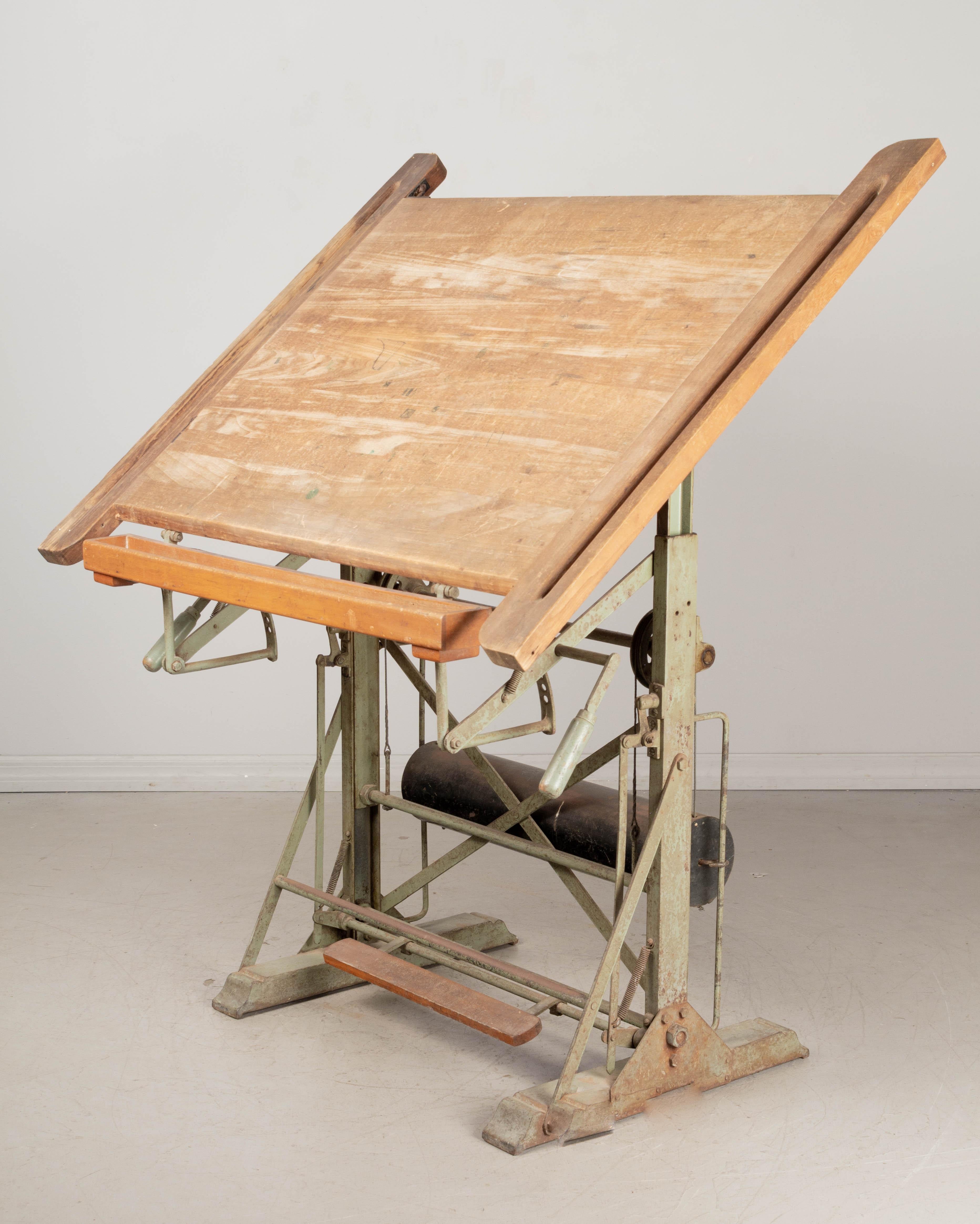 A French Industrial style mechanical architect's drafting table with original green lacquered metal base and large solid elmwood top. The platform is fully modular: using the wood pedal on the front it is possible to raise and lower the top and it