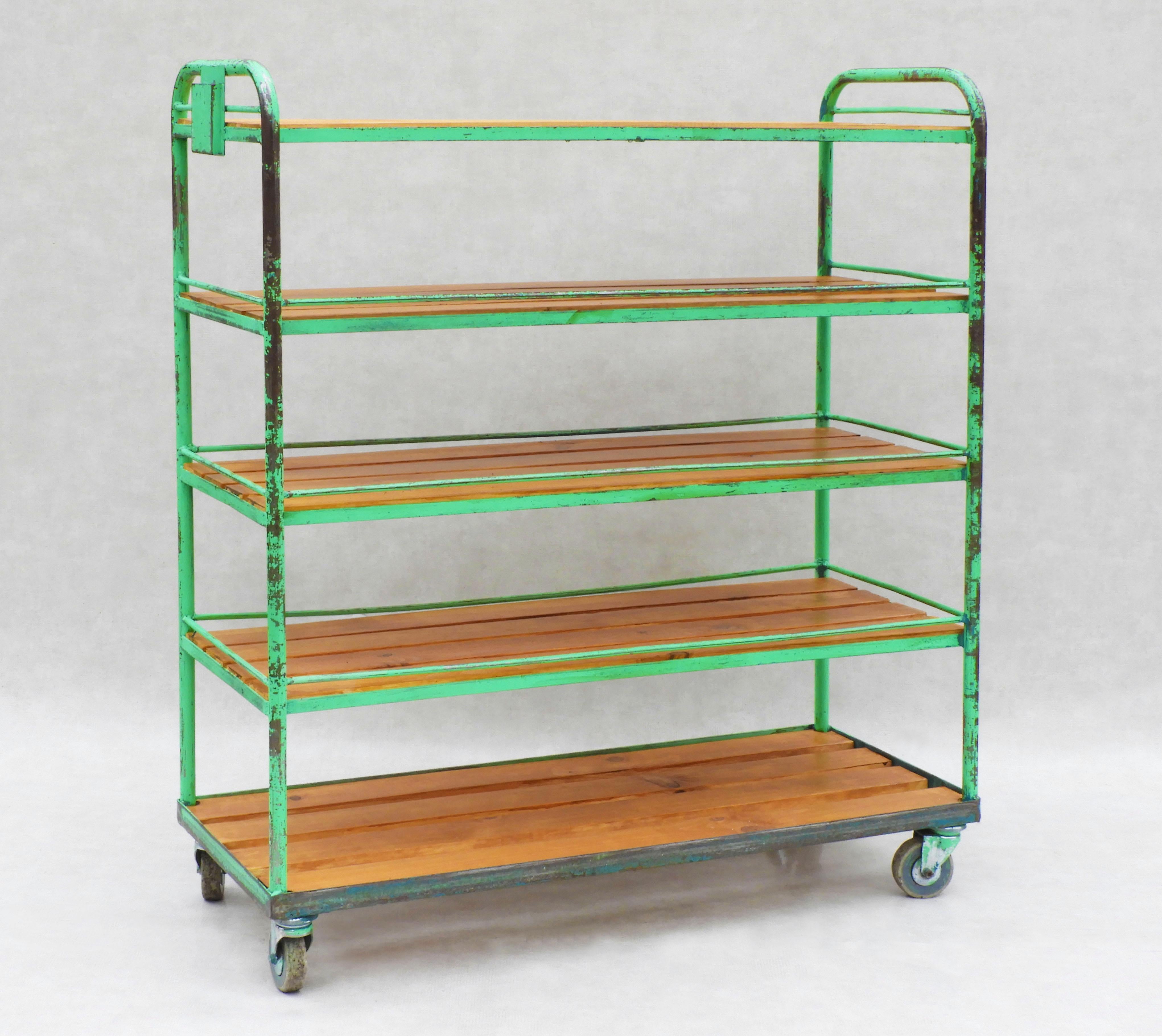 Large Mid century industrial shelving rack on casters.
Five pine slatted shelves on a tubular metal frame with zippy green distressed paintwork on multidirectional wheels.
A fun industrial look perfect for loft design, room divider, kitchen storage