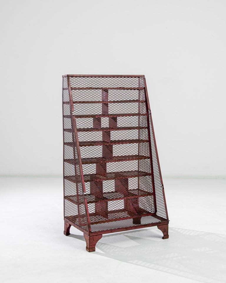 An iron shelving unit from France, produced circa 1960. With the burnt sienna color running throughout its metal mesh body recalling Golden Gate, the slope back of this vintage shelving unit gives it an additional architectural aspect. Featuring