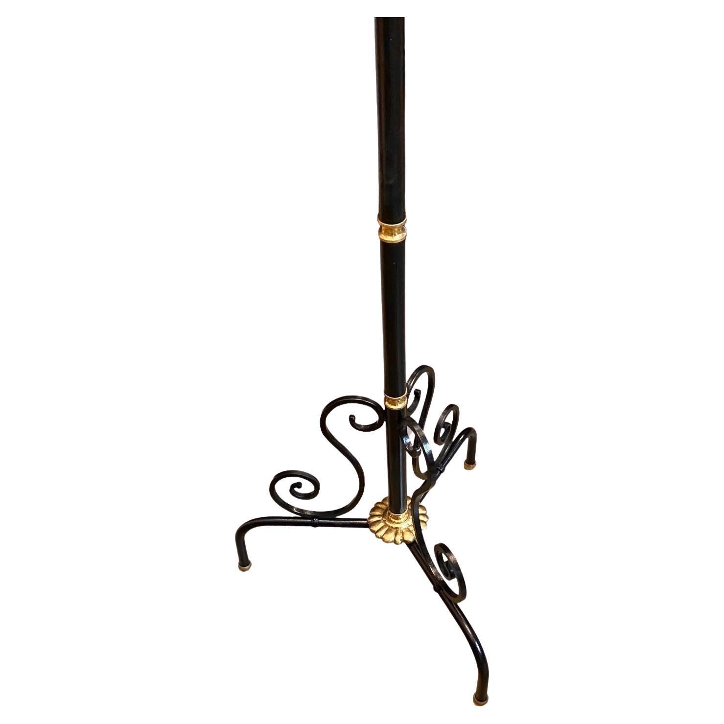 Stunning patinated wrought iron torchiere floor lamp with solid brass details stands on three legs and features three lights with red, black and gold shades. Time earned patina and beautiful detail makes this a statement piece in any space. 