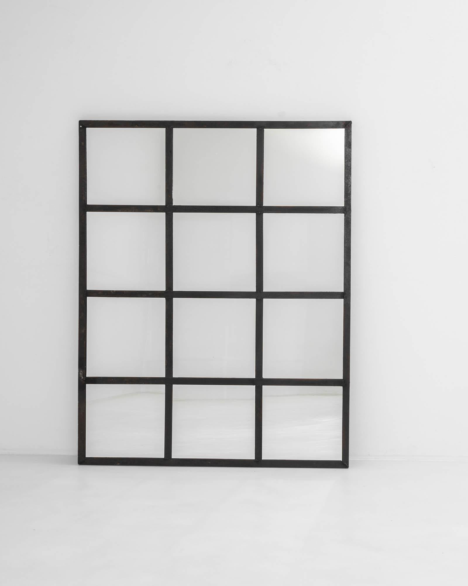 Mimicking the grid patterns of factory architecture, this French vintage-looking glass showcases 12 identical square mirrors enclosed within an industrial iron frame. The original paneled structure adds captivating dimensionality, creating a visual