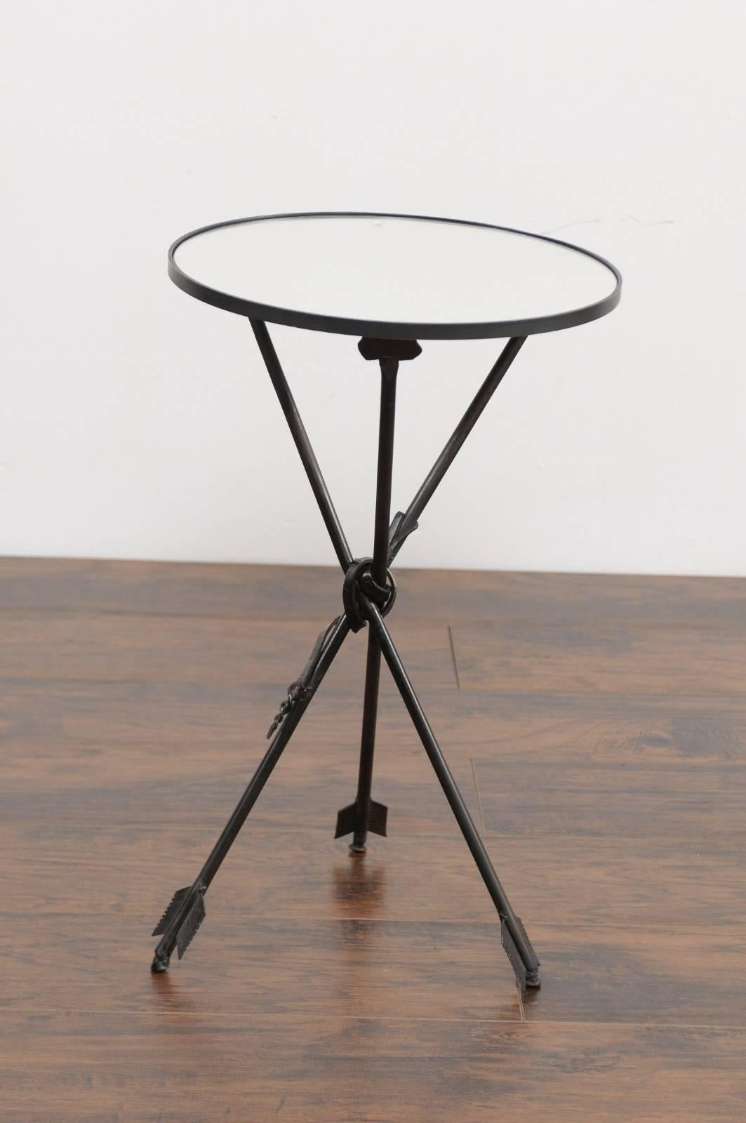 A French vintage round iron side table from the first half of the 20th century with arrow legs and new mirrored top. This French side table features a circular top, adorned with a new custom-made mirror. The table is raised on an exquisite black