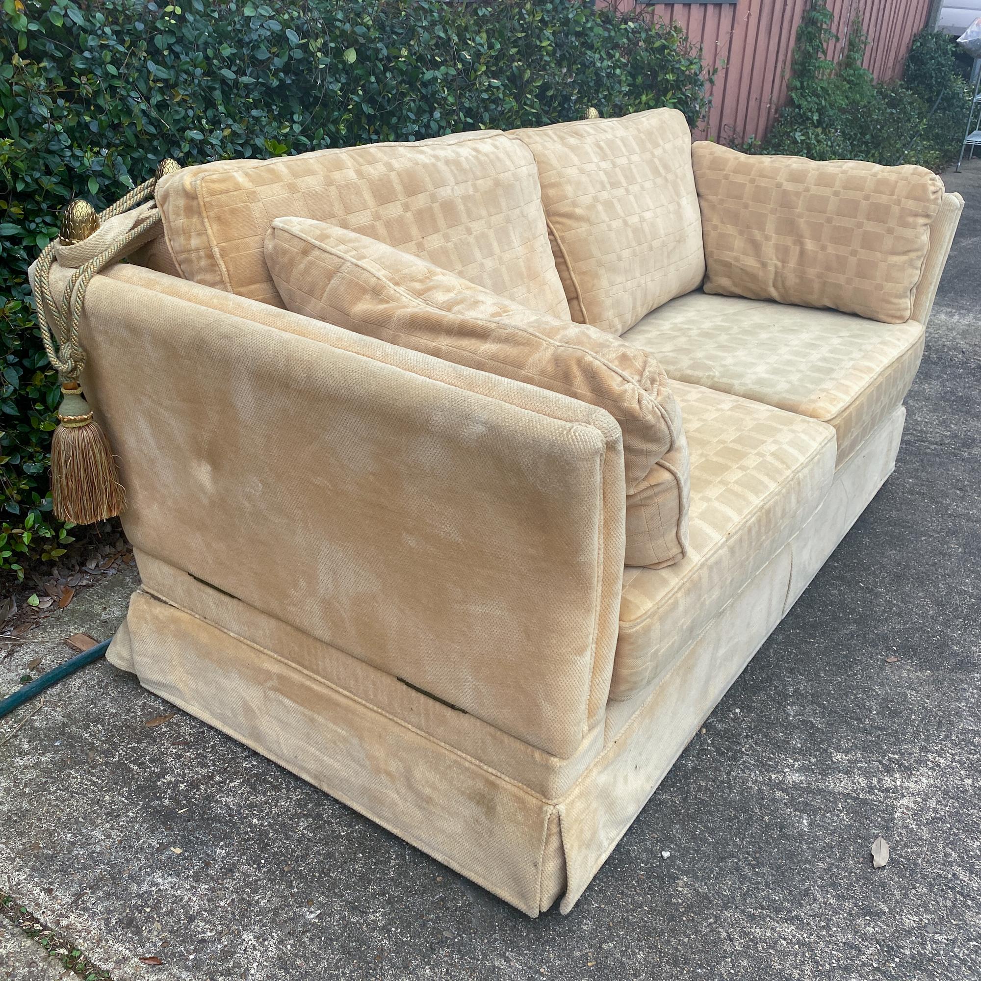 This is a 1970s era canapé sofa made in France, covered in creamy pale yellow velvet with adjustable arms, allowing conversion into a daybed. The piece has brass finial details at the corners of the back and arms to secure the arms in place with