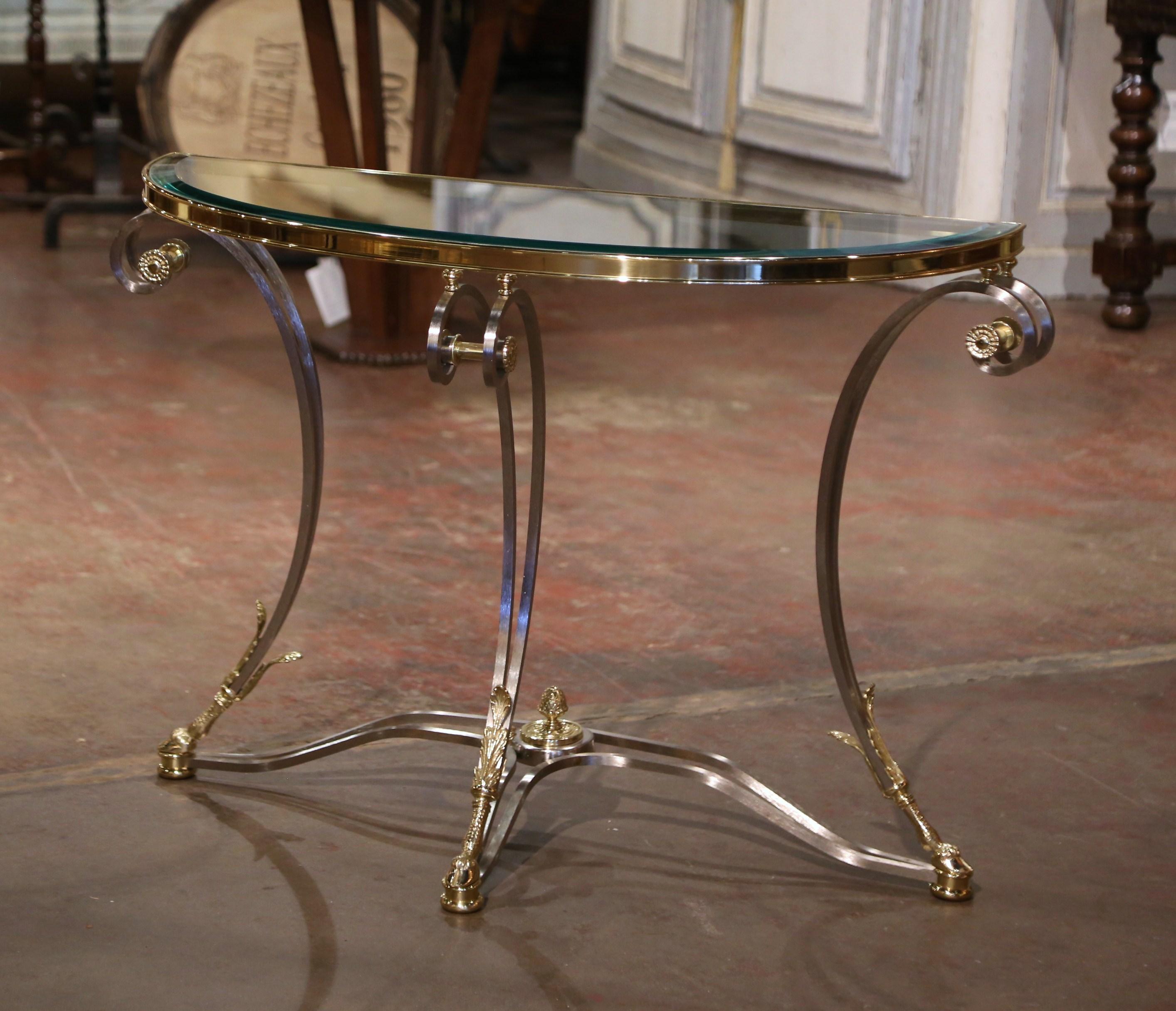 Decorate a living room or den with this elegant demi-lune console table. Created in Paris, France, circa 1980 and attributed to Maison Jansen, the brushed steel and brass table stands on double scrolled legs decorated with acanthus leaves and ending