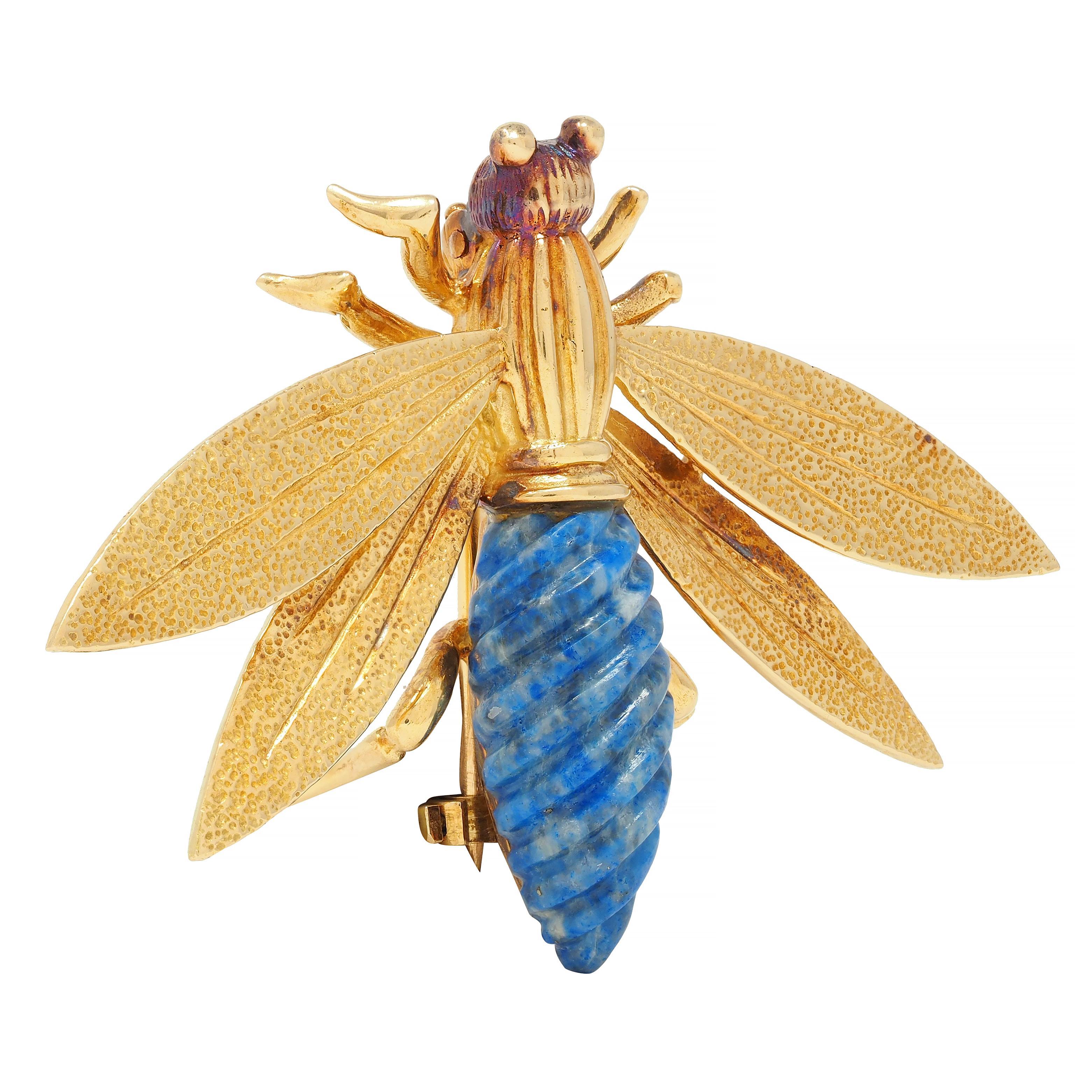 Designed as a stylized insect with four stipple textured wings and a fluted torso
Featuring a carved twist motif lapis lazuli lower body measuring 8.0 x 19.0 mm 
Medium ultramarine blue with gray mottling and pyrite flecking
Accented by beaded eyes